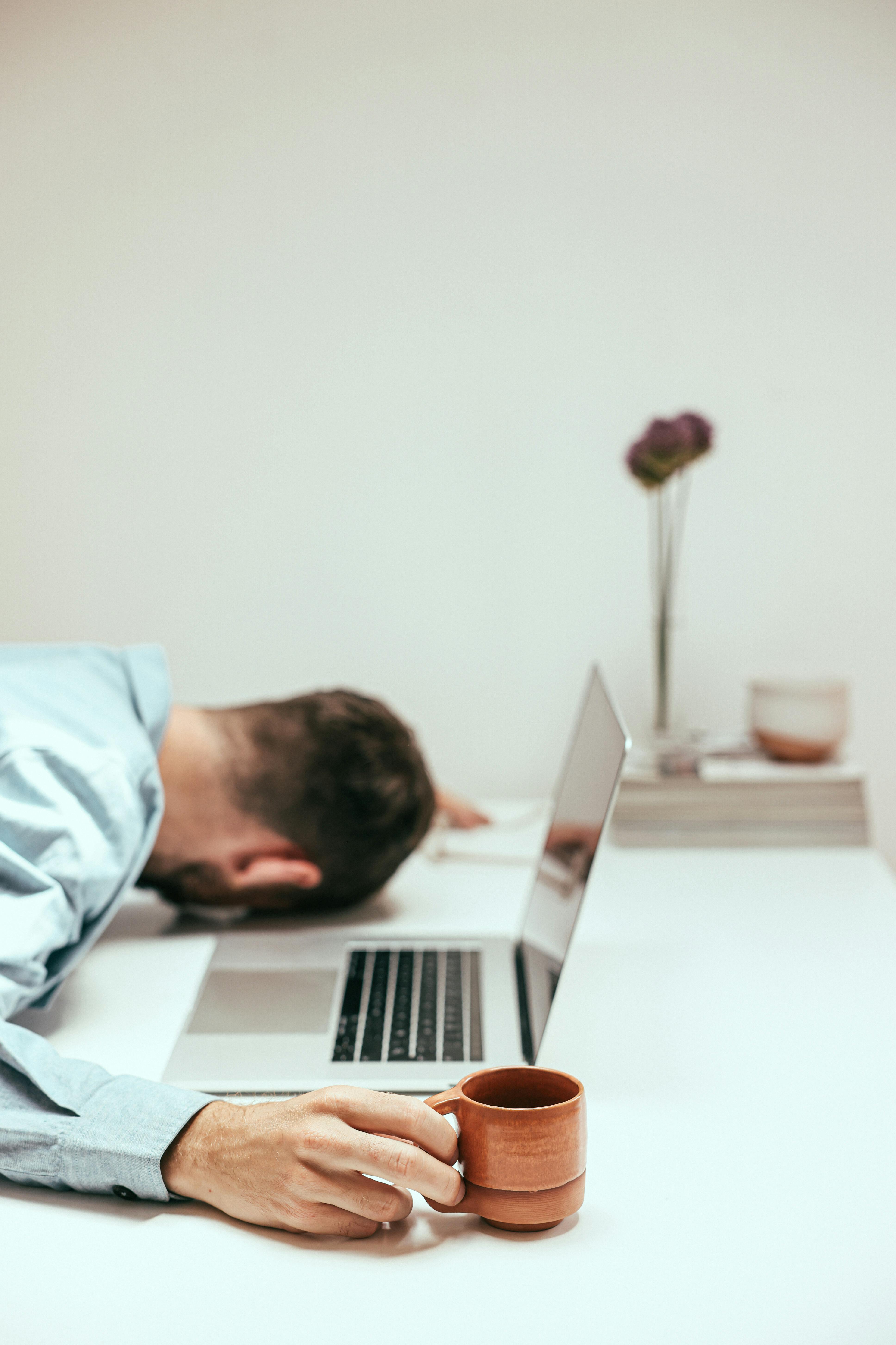 Ein überarbeiteter Mann ruht sich an seinem Schreibtisch aus | Quelle: Pexels