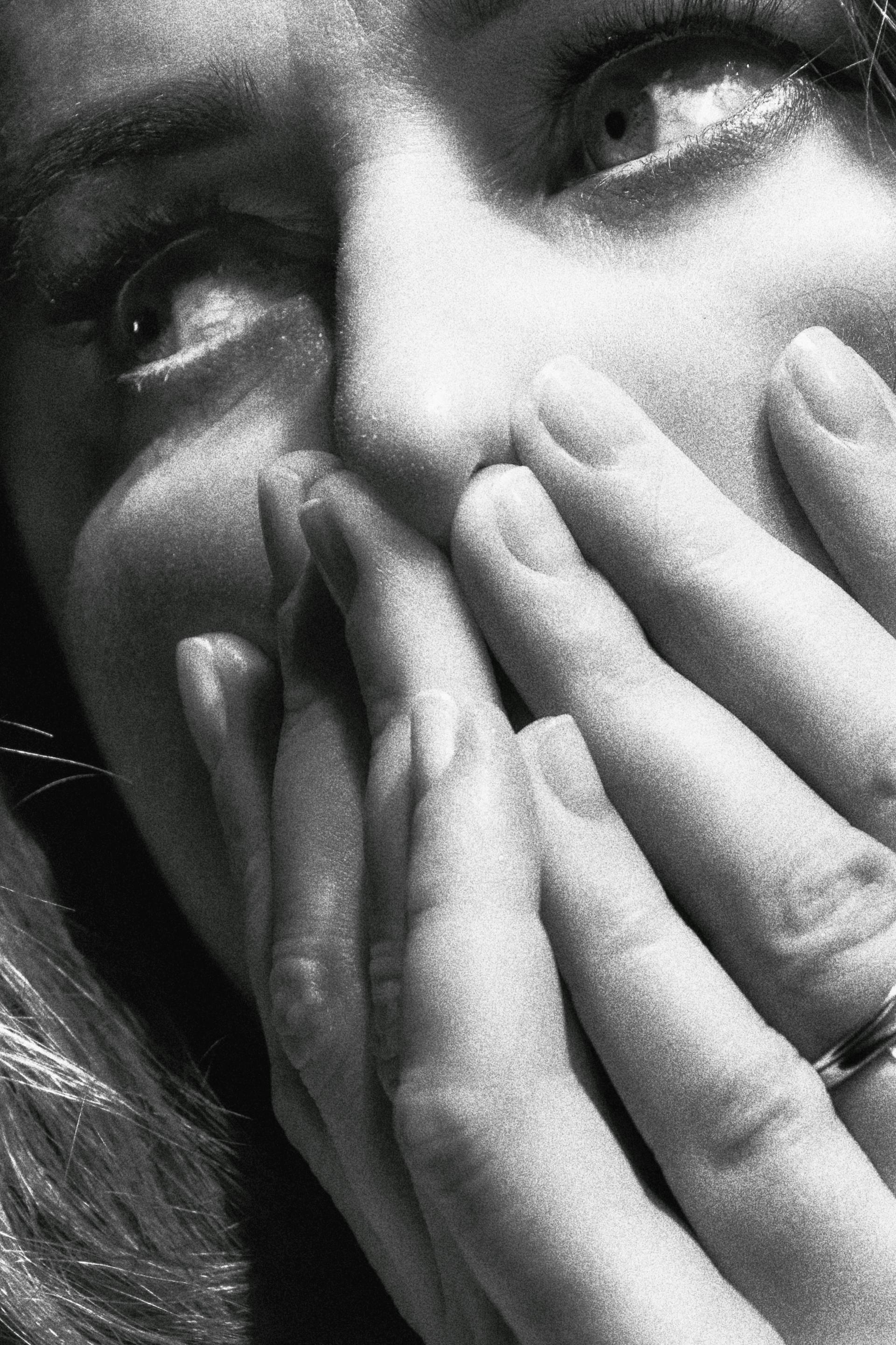 Ein Graustufenfoto von einer Frau, die ihr Gesicht mit den Händen bedeckt | Quelle: Pexels