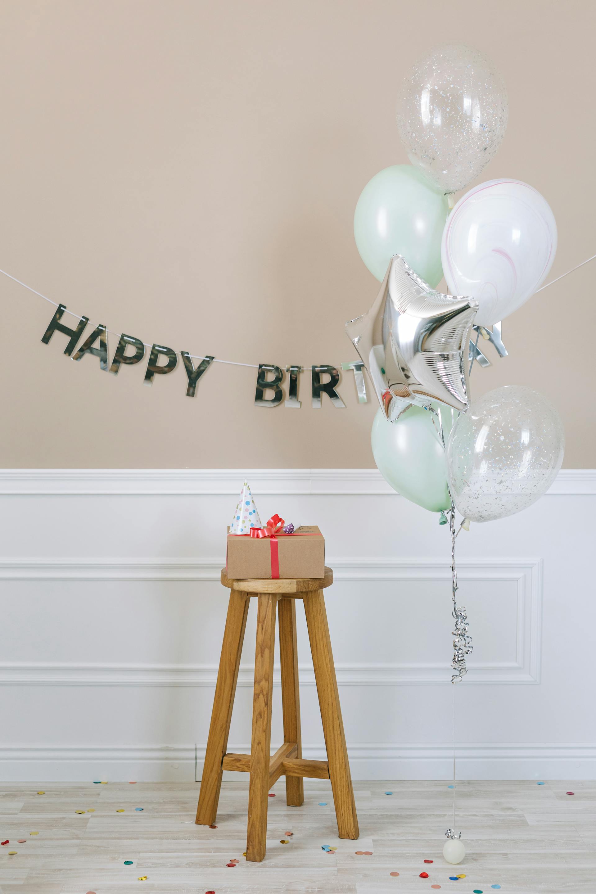 Ein Geburtstagsgeschenk, das auf einem Holzhocker neben Luftballons liegt | Quelle: Pexels