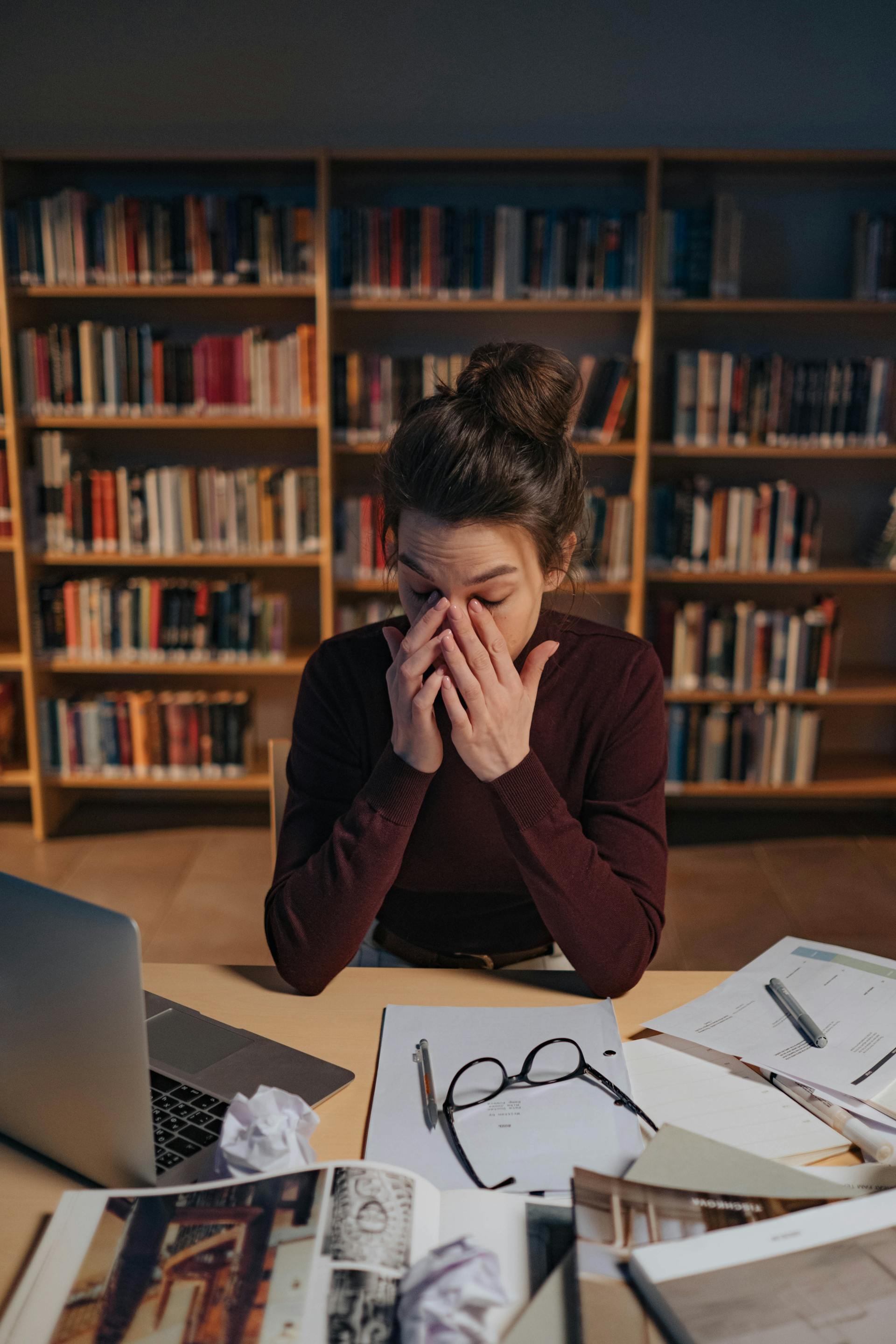 Eine müde Frau arbeitet in einer Bibliothek | Quelle: Pexels