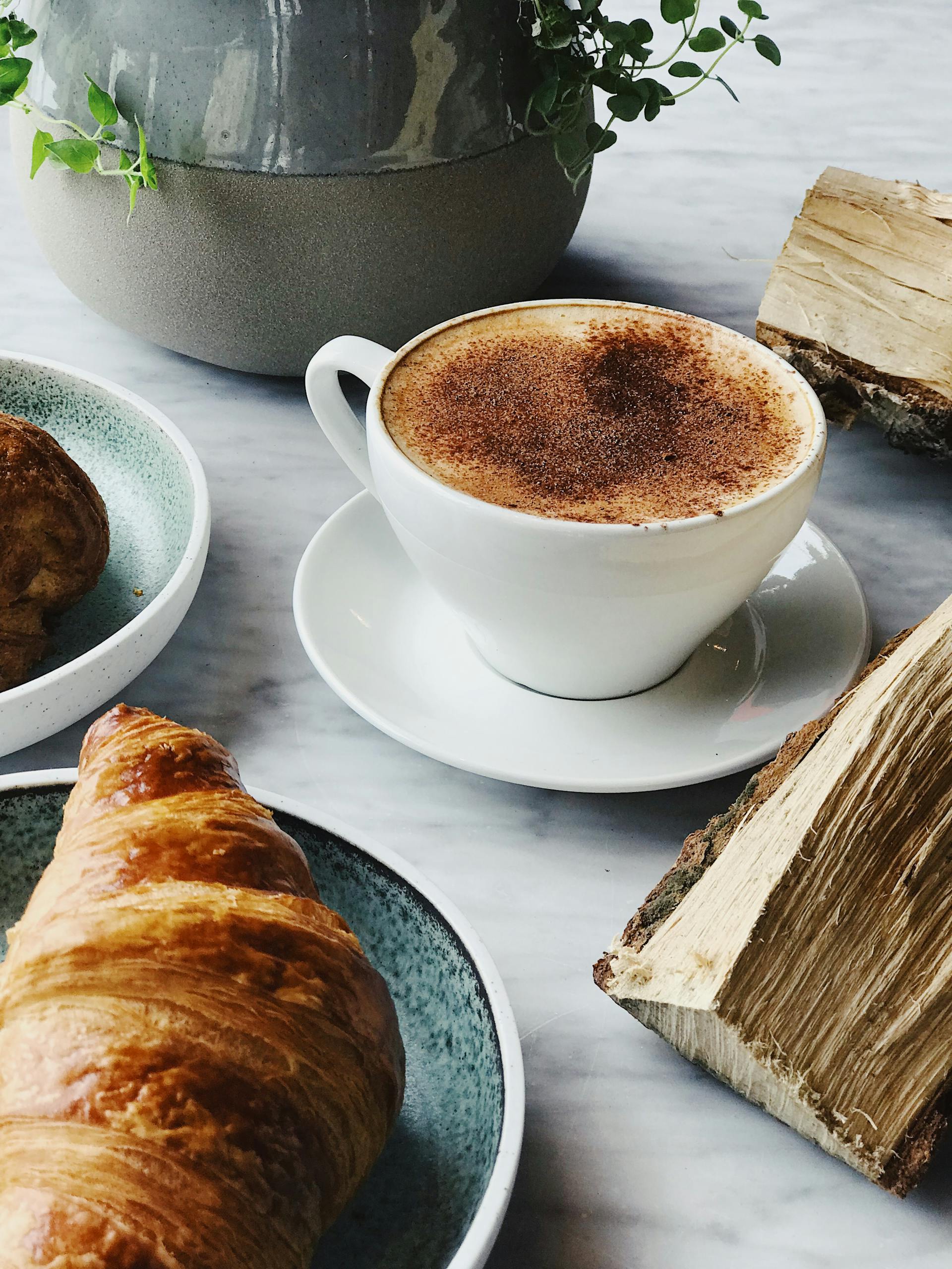 Eine Tasse Kaffee und ein Croissant liegen auf einem Tisch | Quelle: Pexels