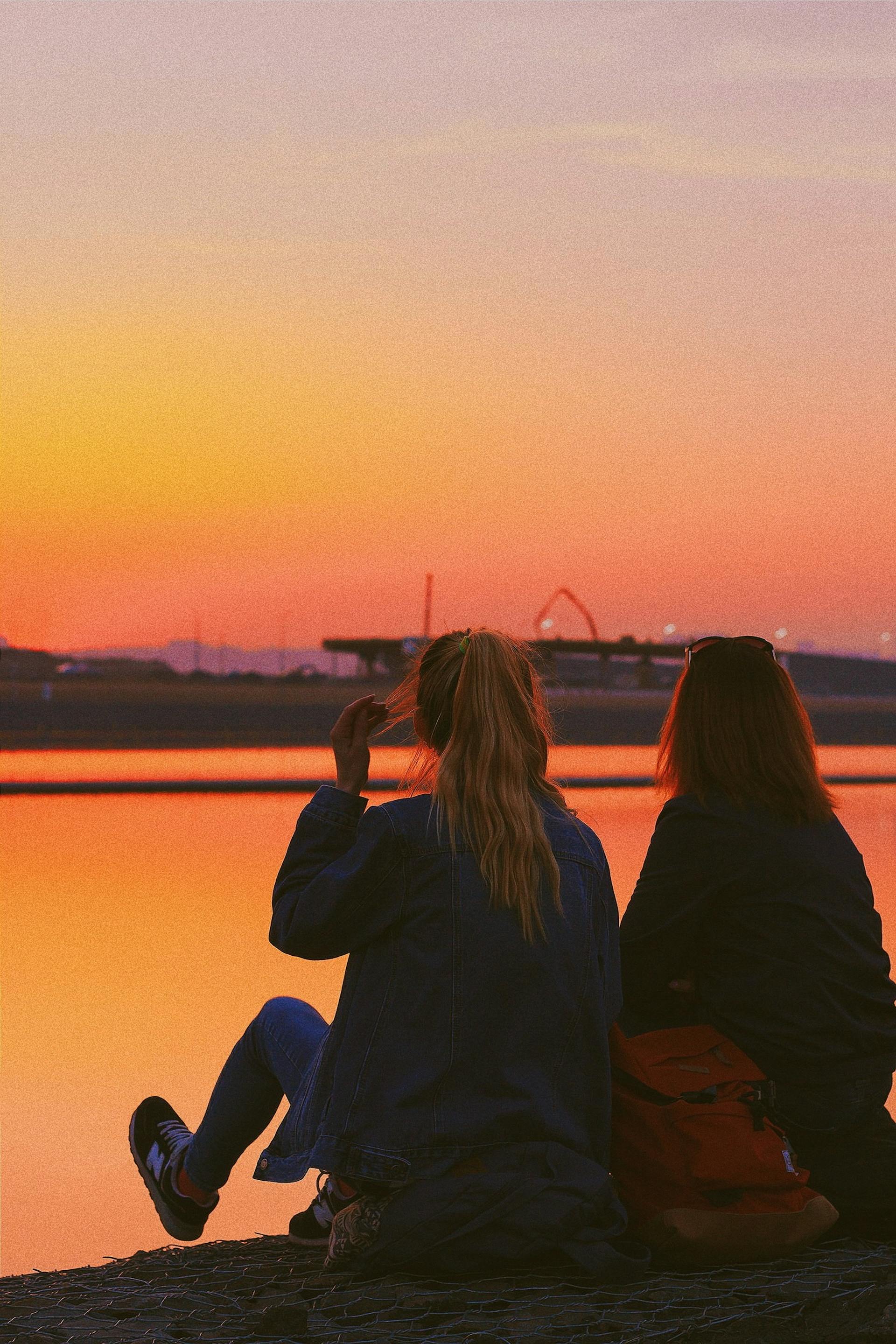 Dwie nastolatki siedzące nad jeziorem | Źródło: Pexels