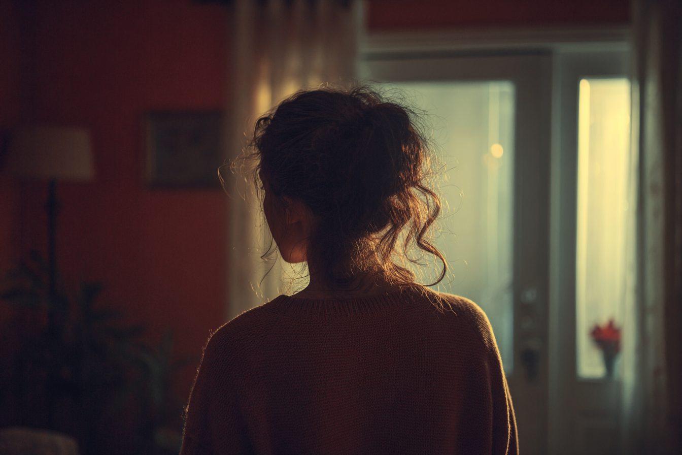 Eine junge Frau steht an einem Fenster | Quelle: Midjourney