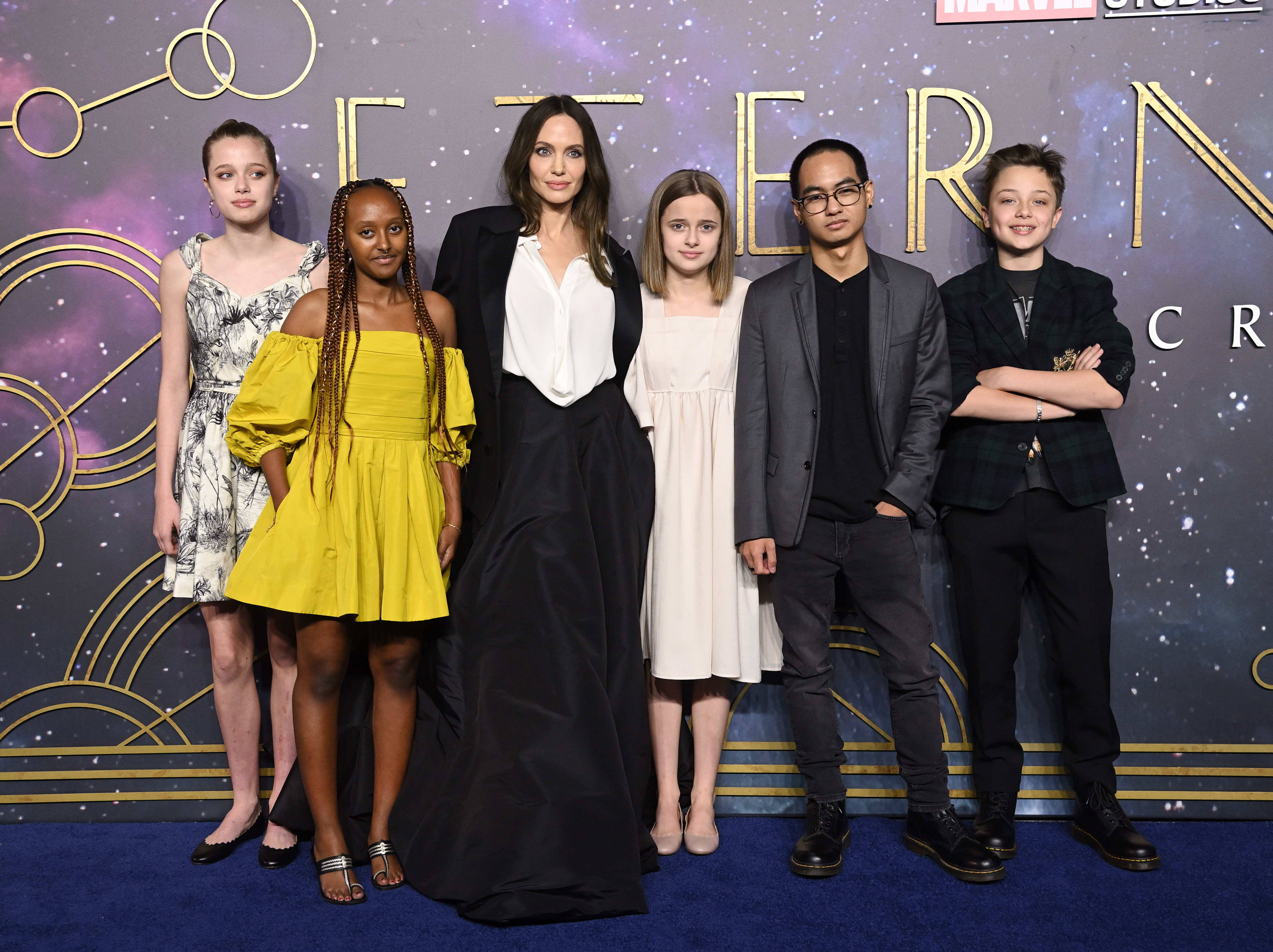 Angelina Jolie posiert bei der europäischen Premiere von „Eternals“ mit ihren sechs Kindern. Sie trägt ein schwarzes, bodenlanges Abendkleid über einer weißen Bluse, während ihre Kinder neben ihr in einer Mischung aus eleganter und legerer Kleidung stehen. Die Familie versammelte sich 2021 auf dem blauen Teppich – Jahre bevor die Frage, ob die Kinder den Nachnamen Jolie tragen, wieder in den Fokus rückte. | Quelle: Getty Images