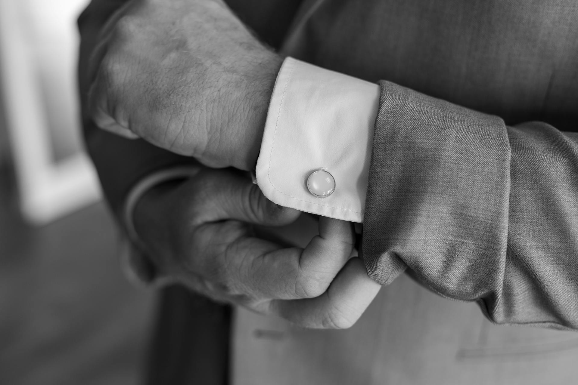 Graustufenfoto eines Mannes, der seinen Manschettenknopf zurechtrückt | Quelle: Pexels