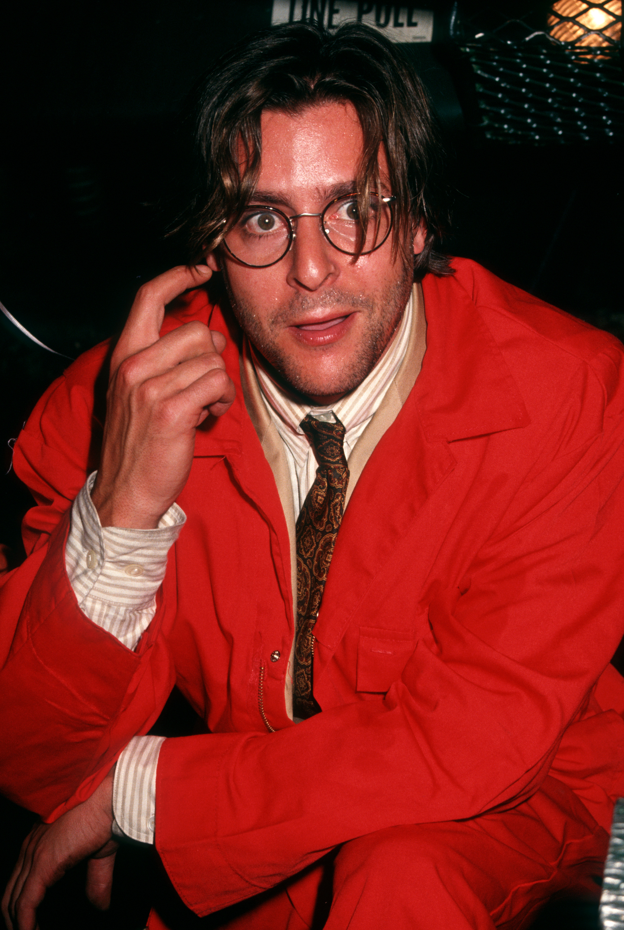 Der Schauspieler, der in einem knallroten Overall, einer Brille mit rundem Rahmen und einer gemusterten Krawatte eine verspielte Pose einnahm, feierte die Premierenparty für