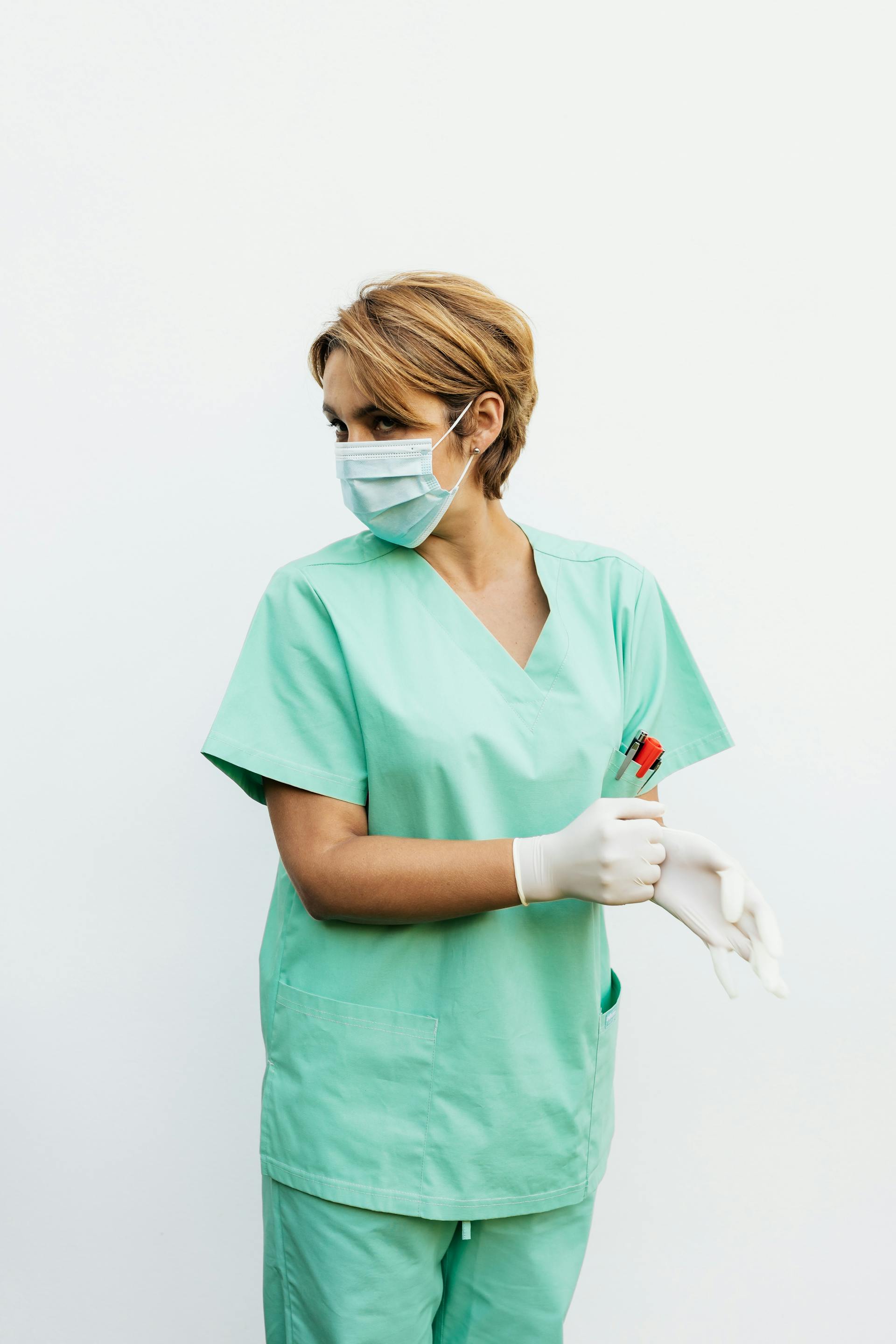 Eine Krankenschwester in Kittel und Gesichtsmaske schaut zurück | Quelle: Pexels