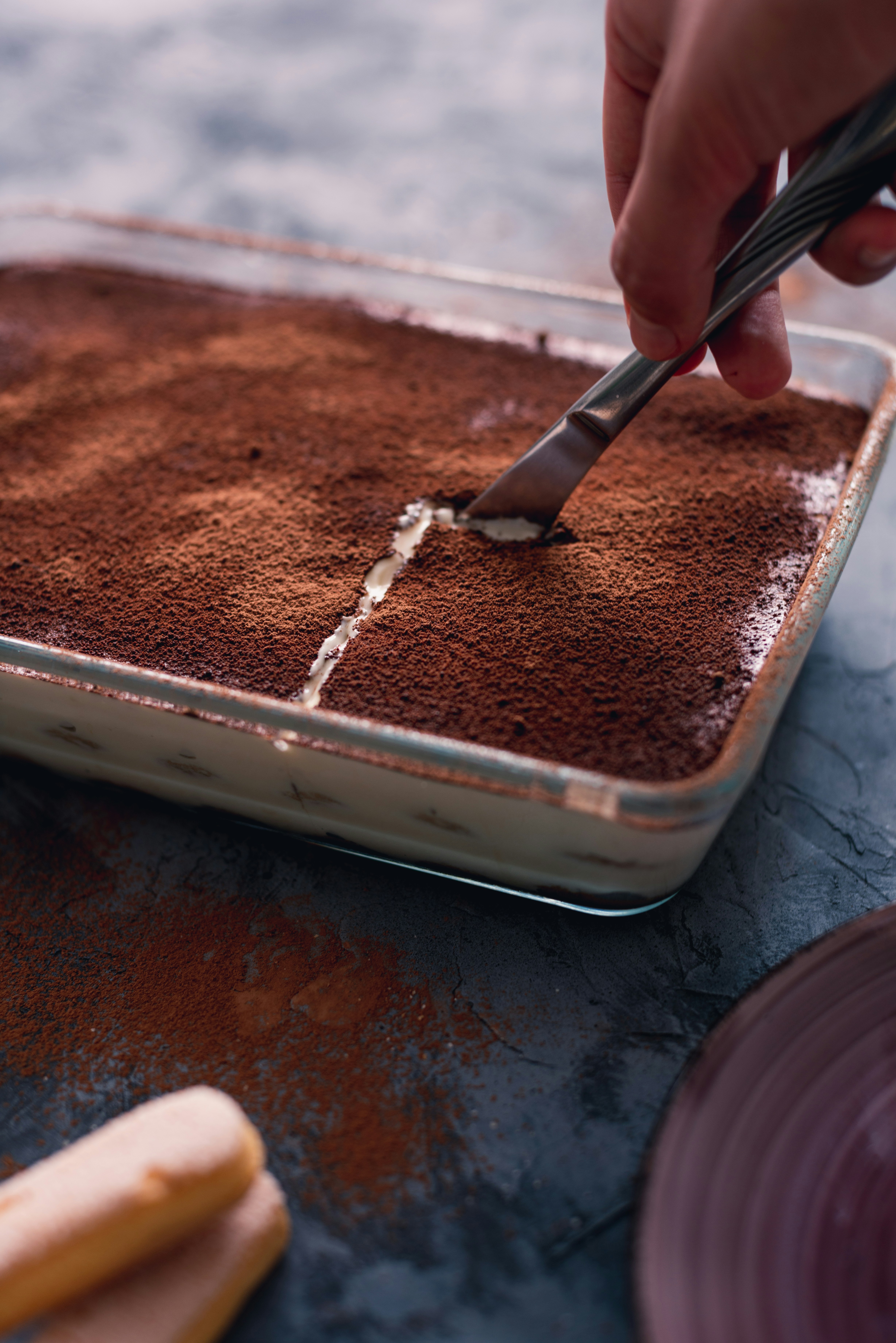 Eine Person, die ein Stück Tiramisu anschneidet | Quelle: Unsplash