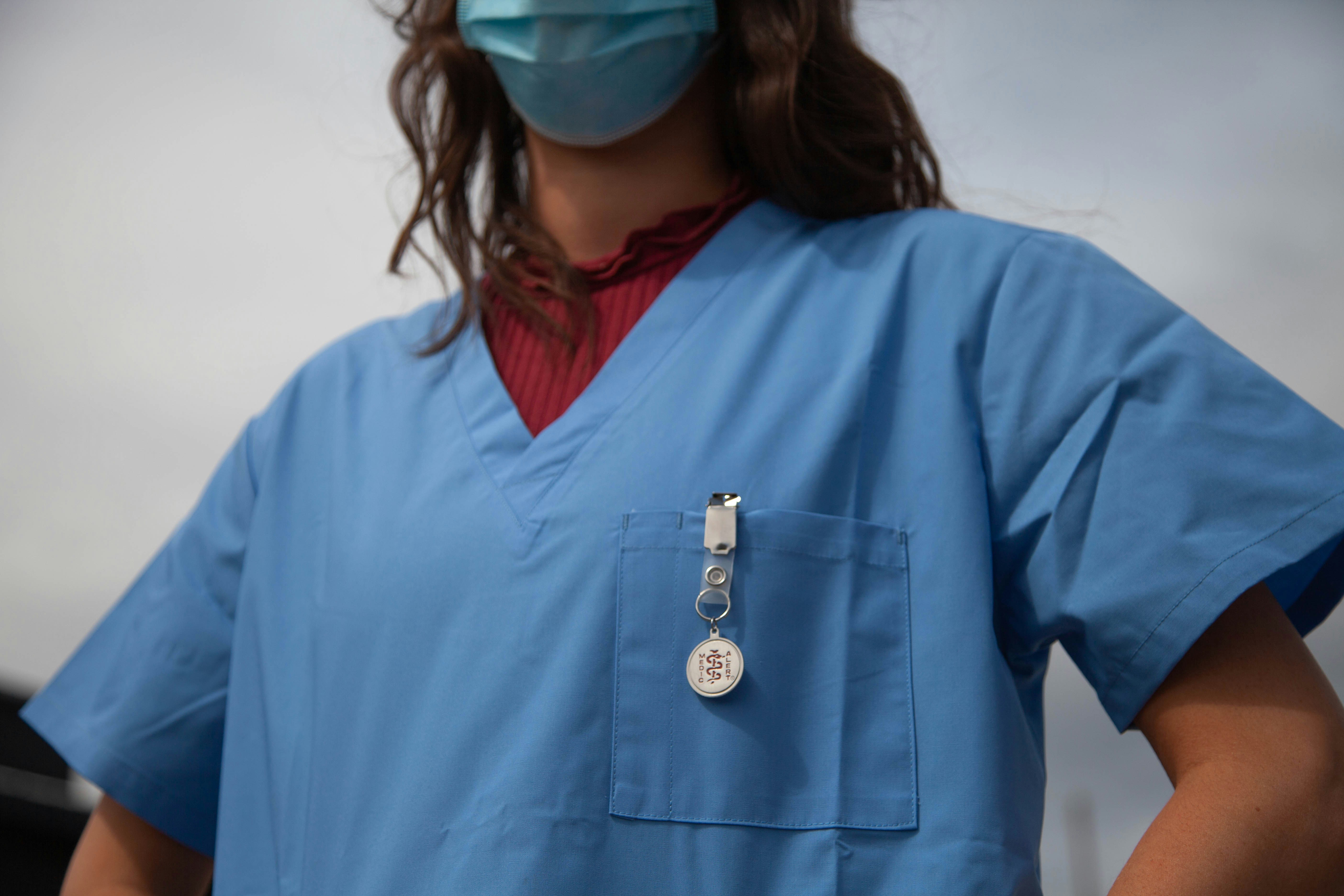 Eine Frau mit blauem Kittel und Maske | Quelle: Unsplash