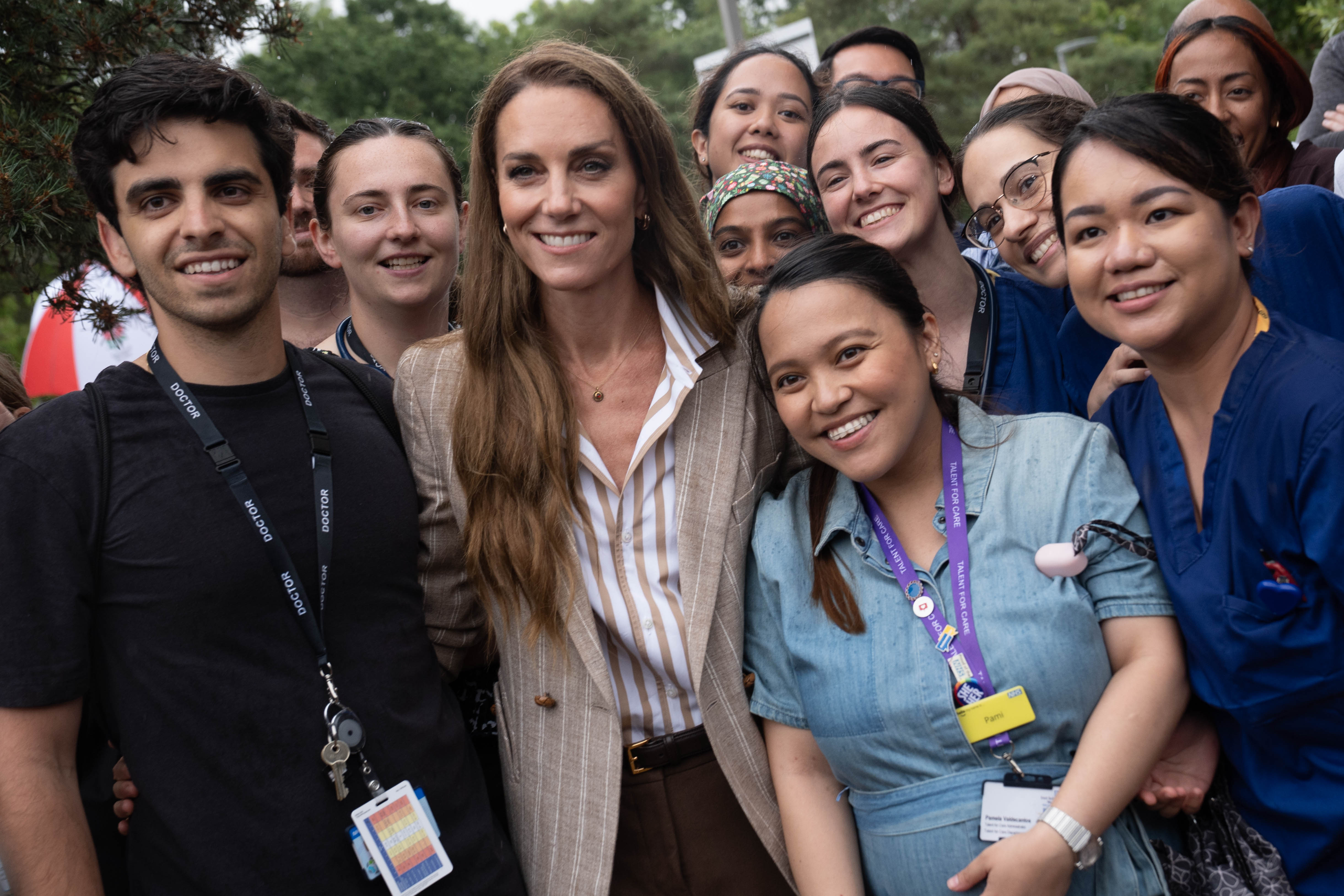 Umgeben von strahlenden Krankenhausmitarbeitern posiert Prinzessin Catherine für ein Gruppenfoto und ihr Lächeln spiegelt die Freude derer wider, die mit ihr Seite an Seite stehen.