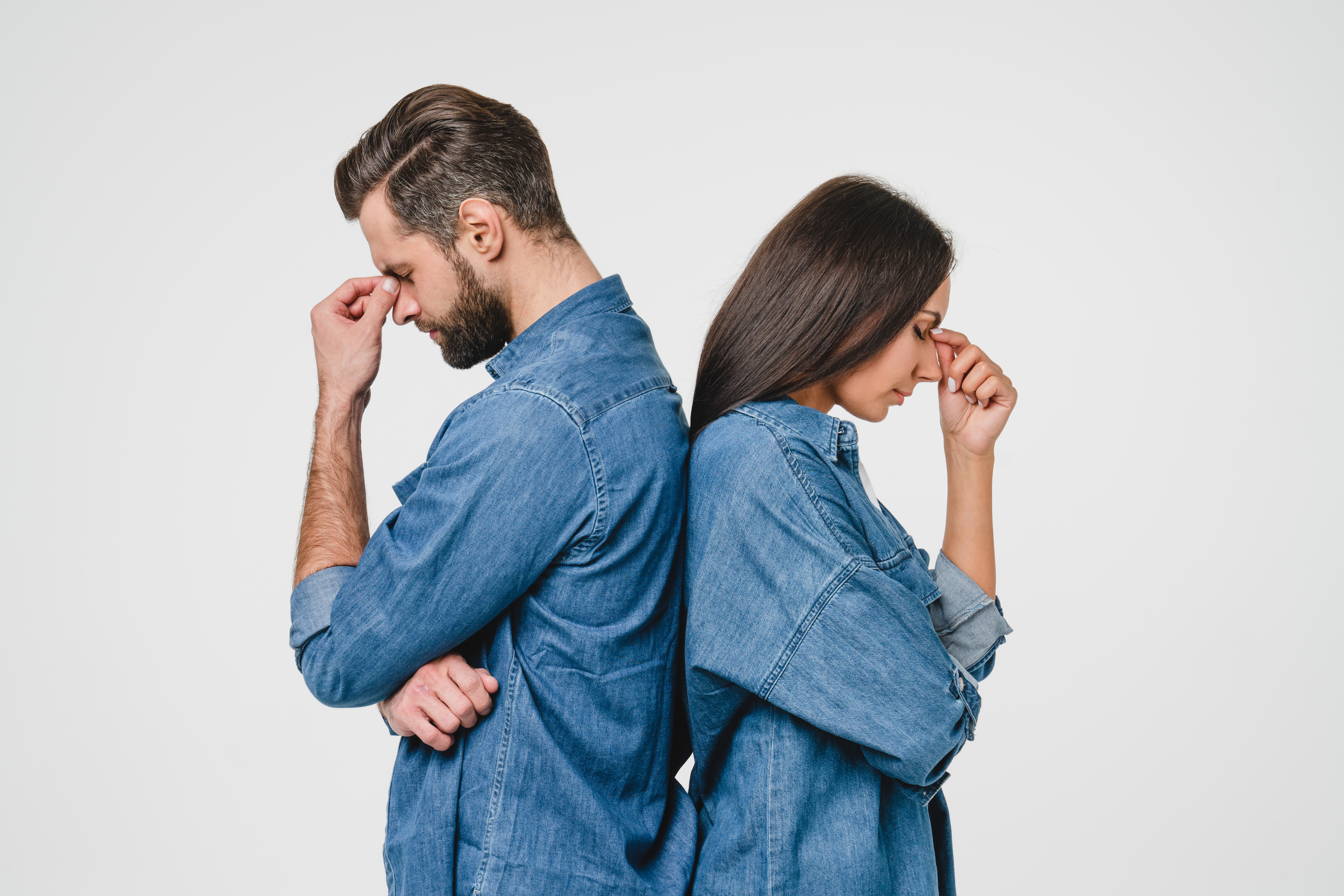 Mężczyzna i kobieta stojący tyłem do siebie z głowami w dłoniach | Źródło: Shutterstock