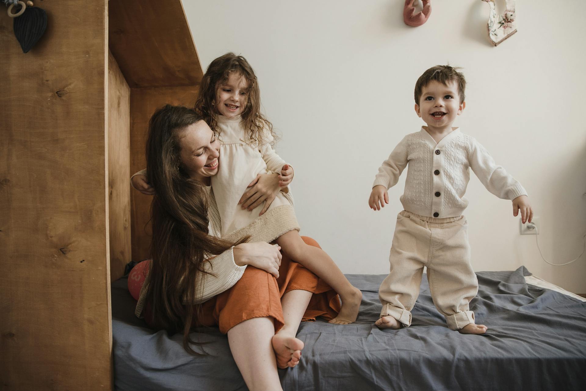 Eine Frau spielt mit ihren Kindern auf dem Bett | Quelle: Pexels