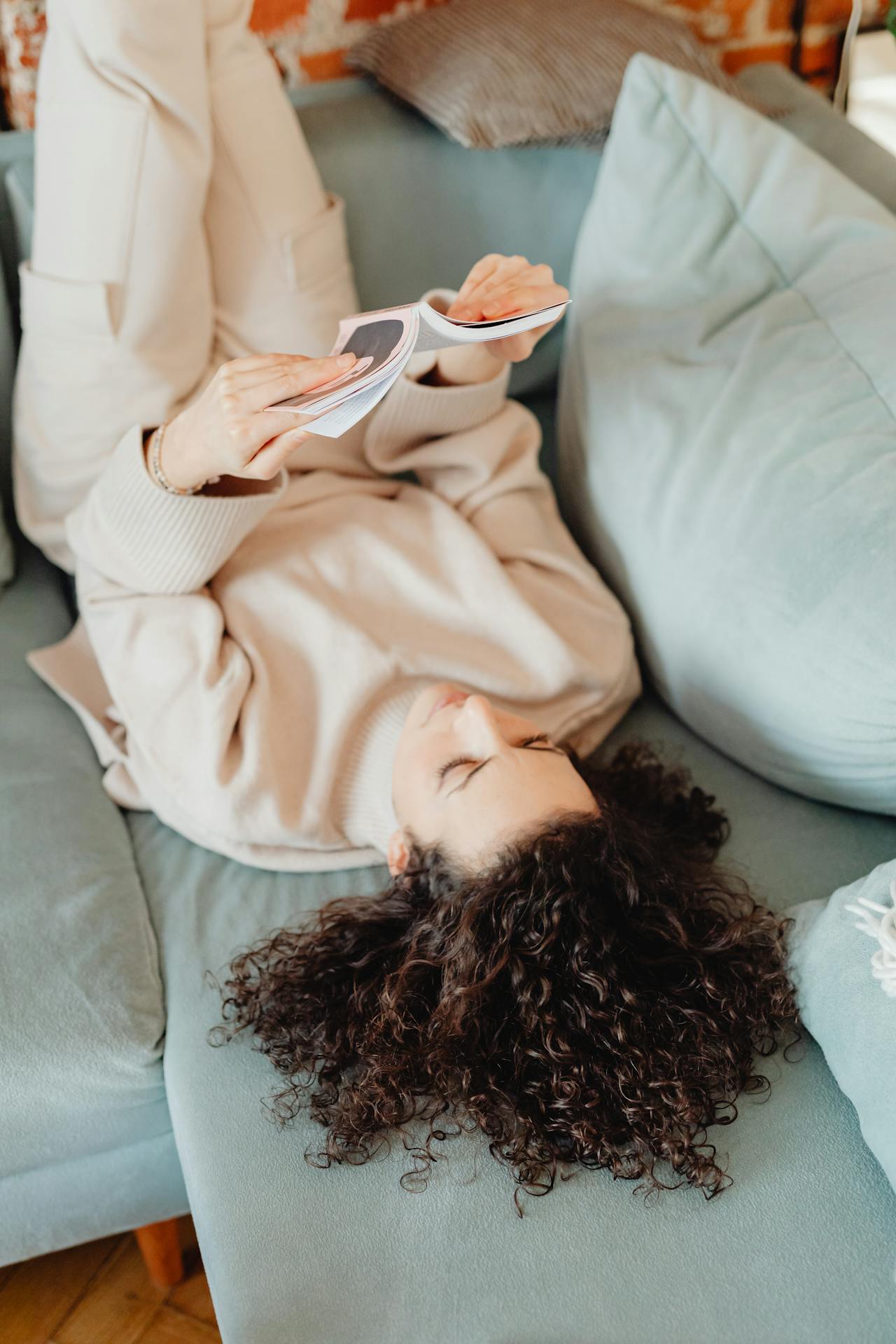 Eine Frau, die auf der Couch liegt und ein Buch liest | Quelle: Pexels