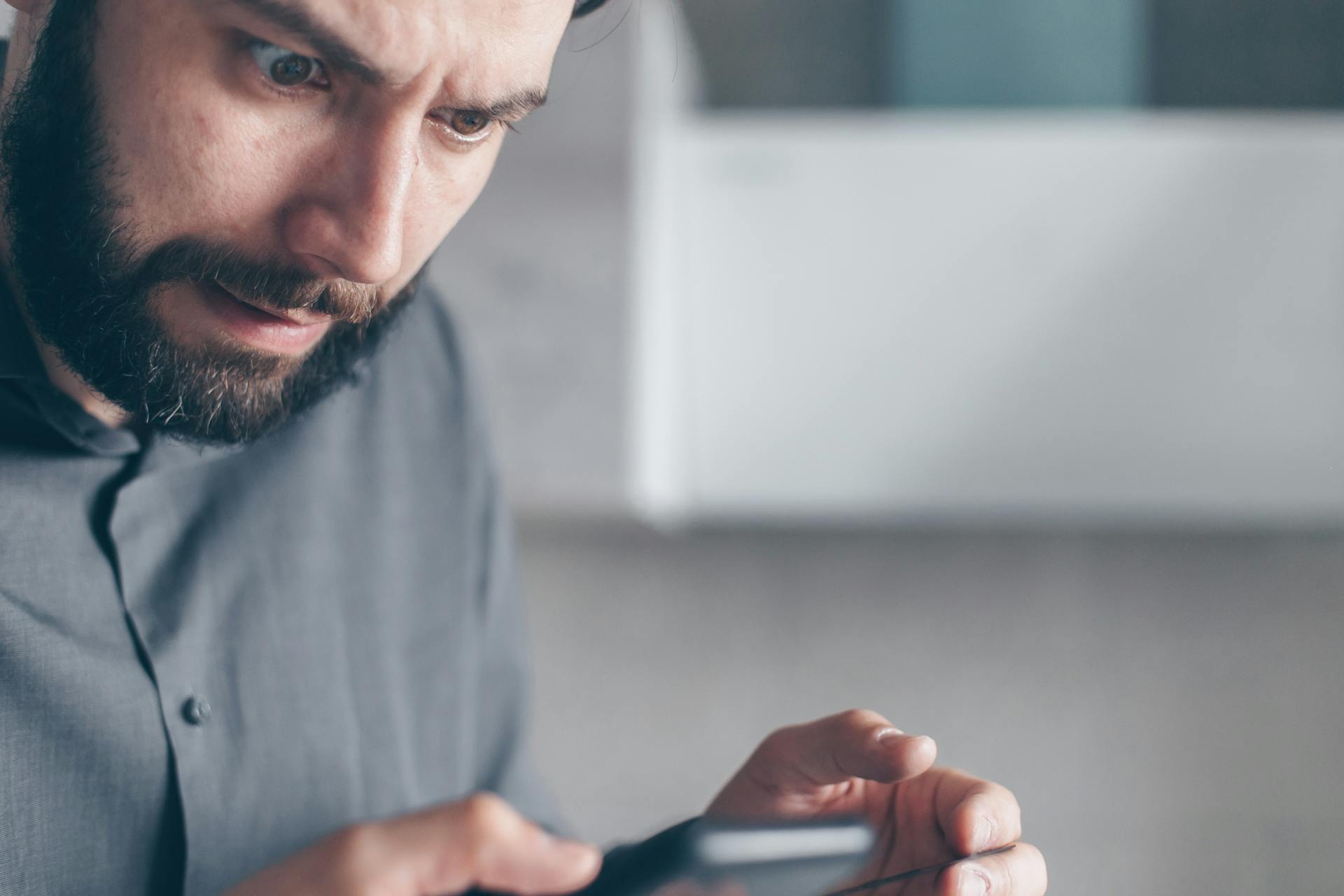 Ein Mann, der geschockt auf sein Handy starrt | Quelle: Pexels