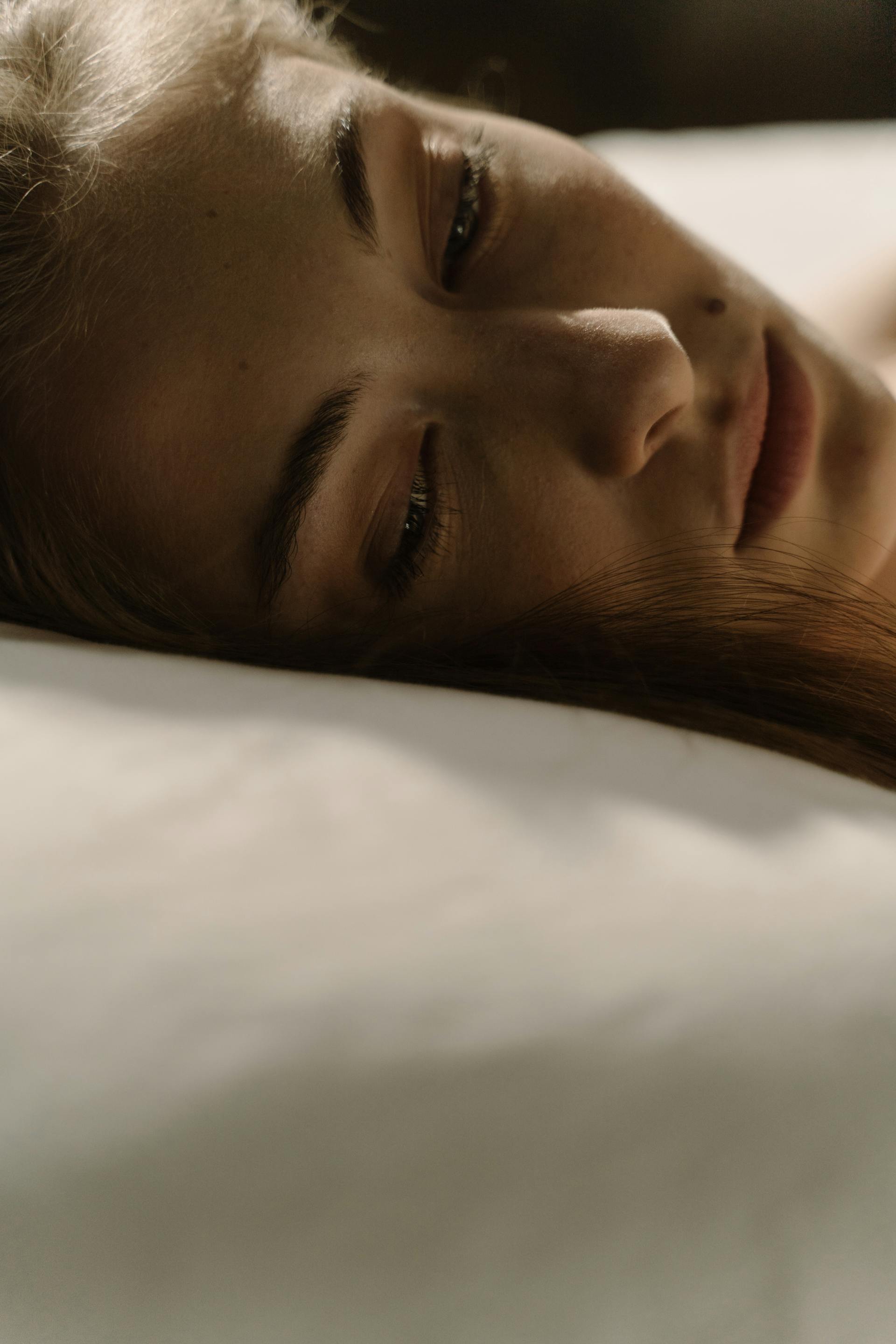 Eine Nahaufnahme einer Frau, die wach im Bett liegt | Quelle: Pexels