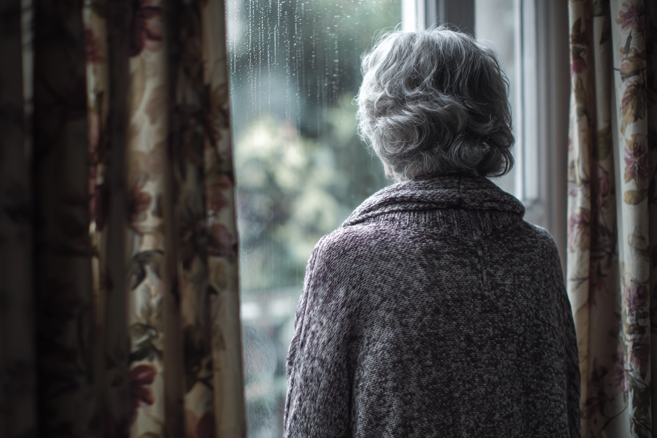 Eine ältere Frau, die an einem Fenster steht | Quelle: Midjourney