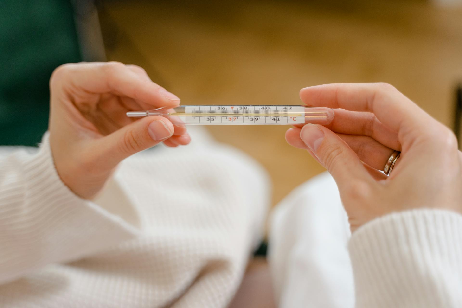 Eine Frau hält ein Thermometer | Quelle: Pexels