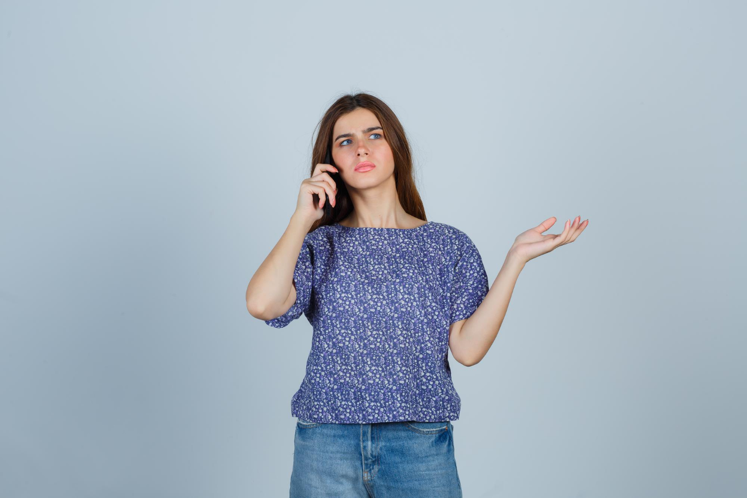 Eine entmutigte junge Frau beim Telefonieren | Quelle: Freepik