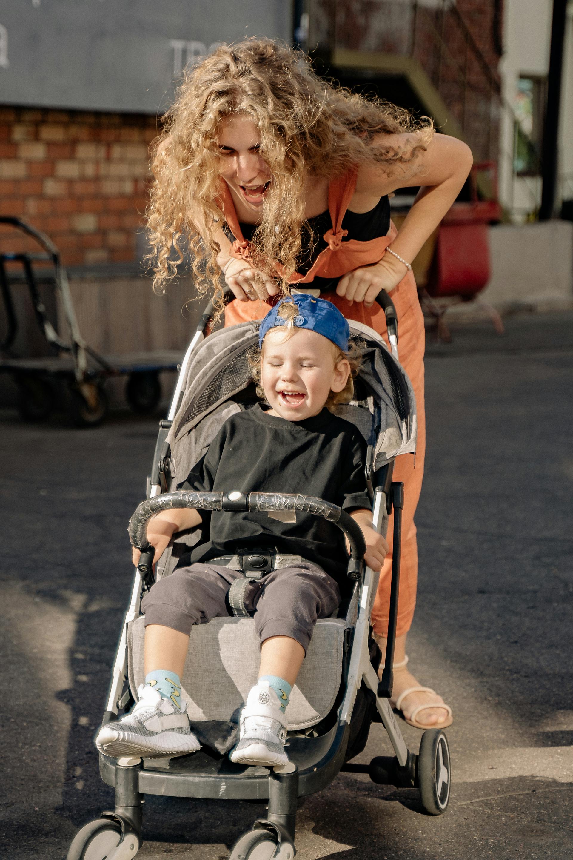 Eine Frau hat Spaß mit ihrem Sohn im Kinderwagen | Quelle: Pexels