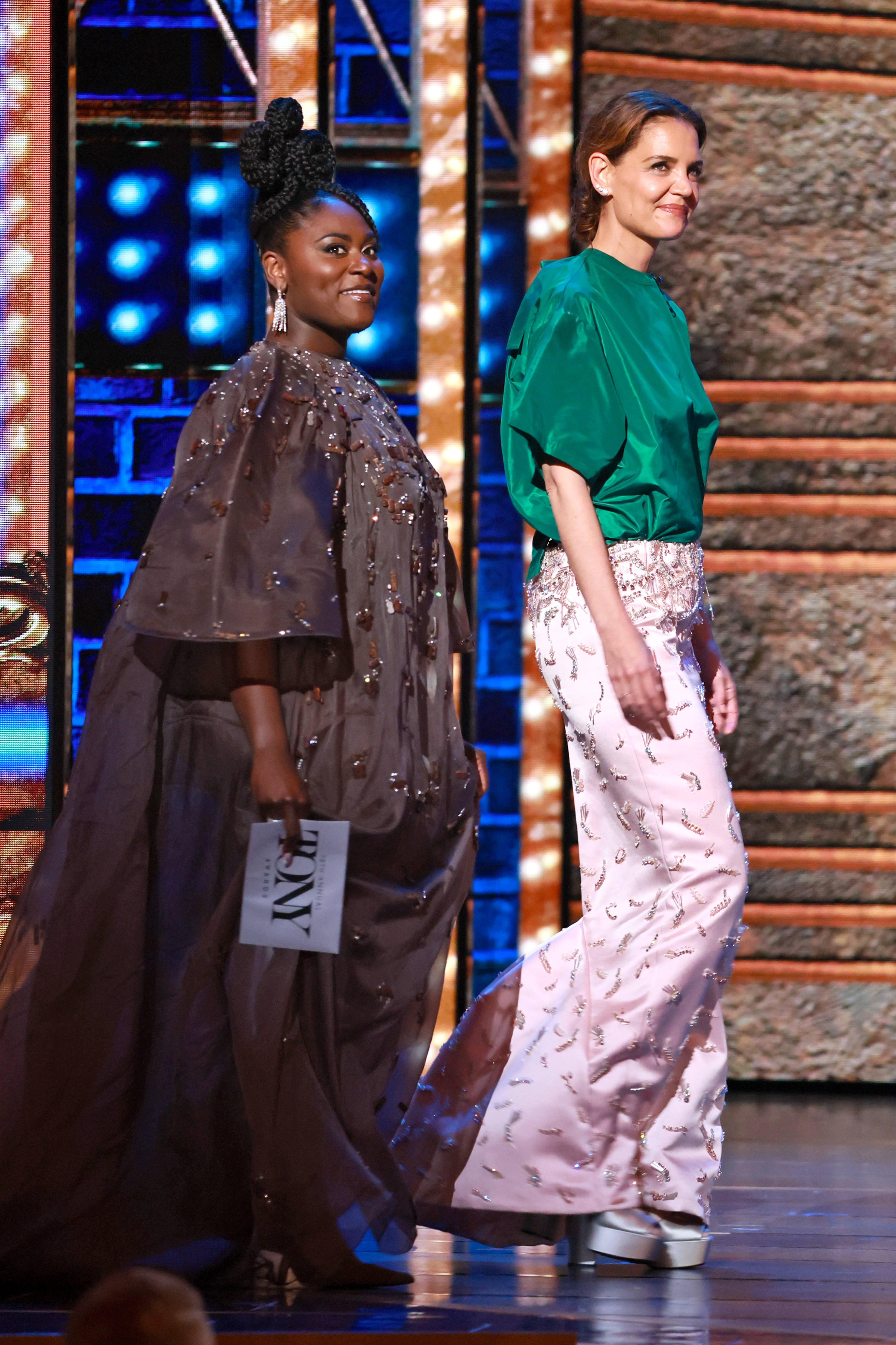 Katie Holmes betritt die Bühne während der 78th Annual Tony Awards an der Seite von Danielle Brooks und präsentiert souverän und lächelnd in einem auffälligen grünen Top und einem rosafarbenen Rock in der Radio City Music Hall am 8. Juni 2025.