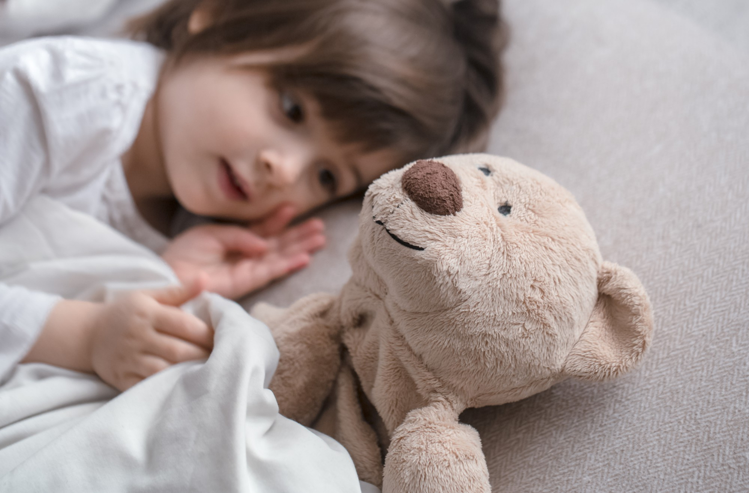 Ein kleines Mädchen liegt neben ihrem Teddybär | Quelle: Freepik