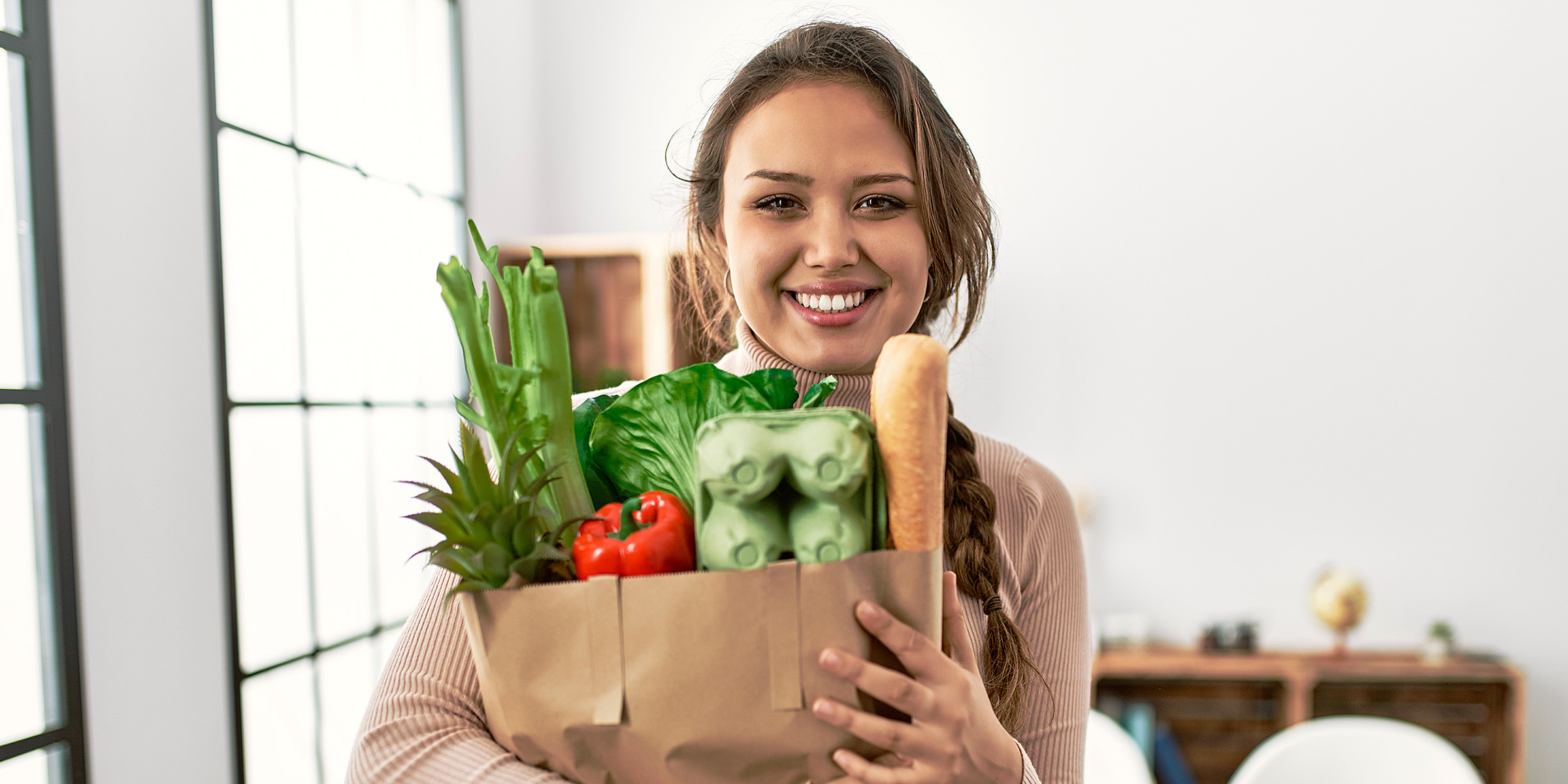 Eine Frau hält eine Tüte mit Lebensmitteln | Quelle: Shutterstock