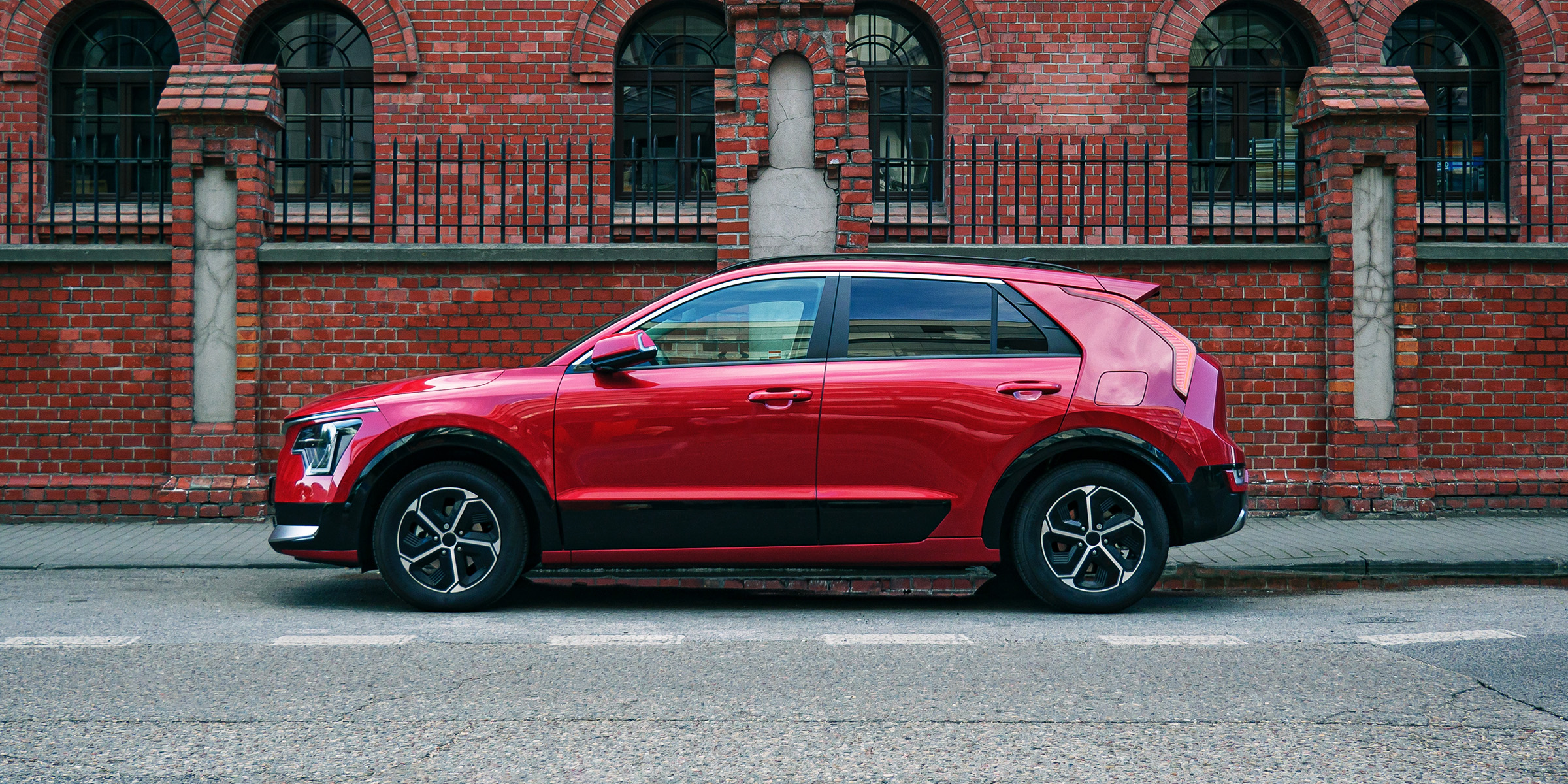 Ein roter SUV parkt neben einem Backsteingebäude | Quelle: Shutterstock