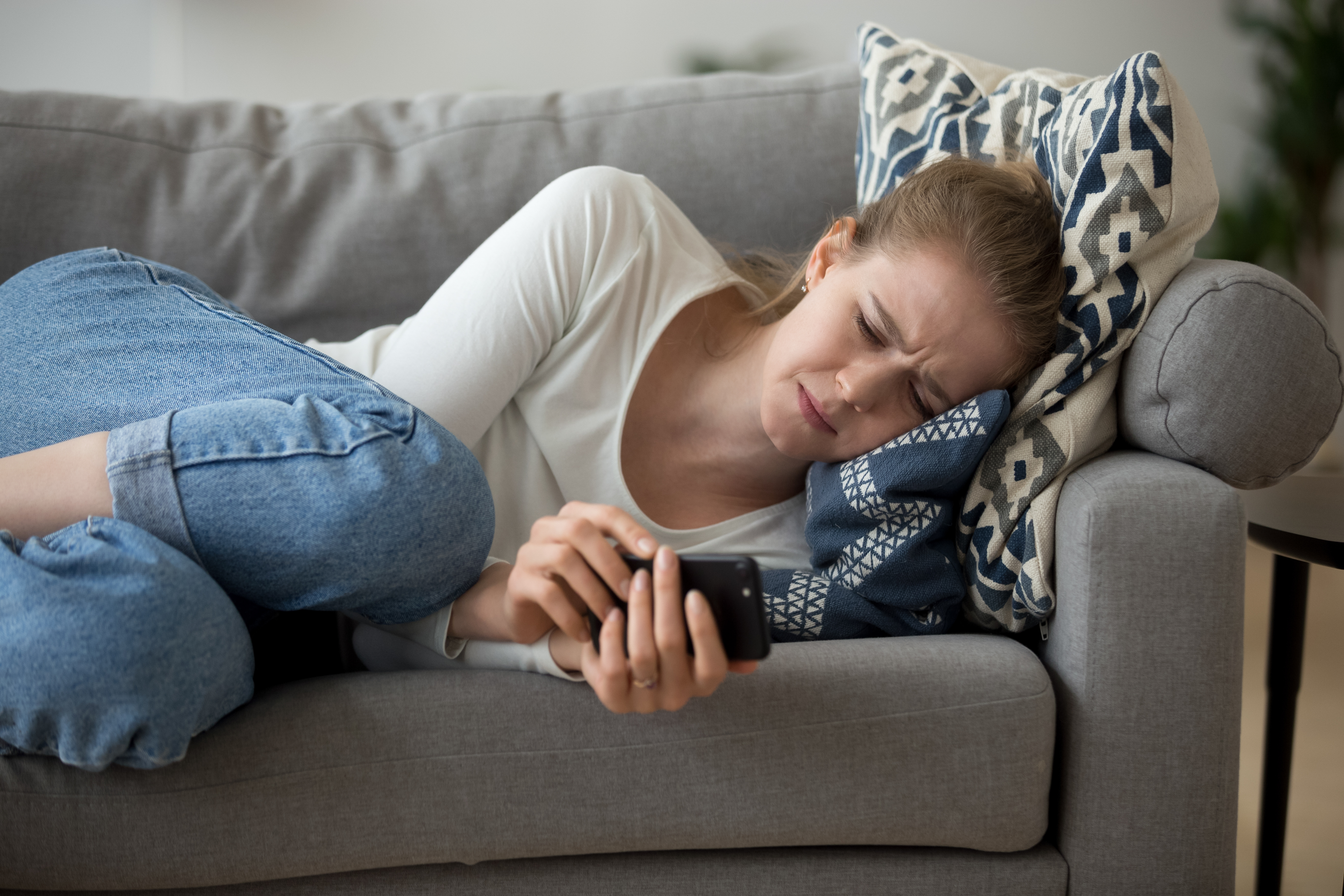 Zdenerwowana kobieta leżąca na sofie | Źródło: Shutterstock
