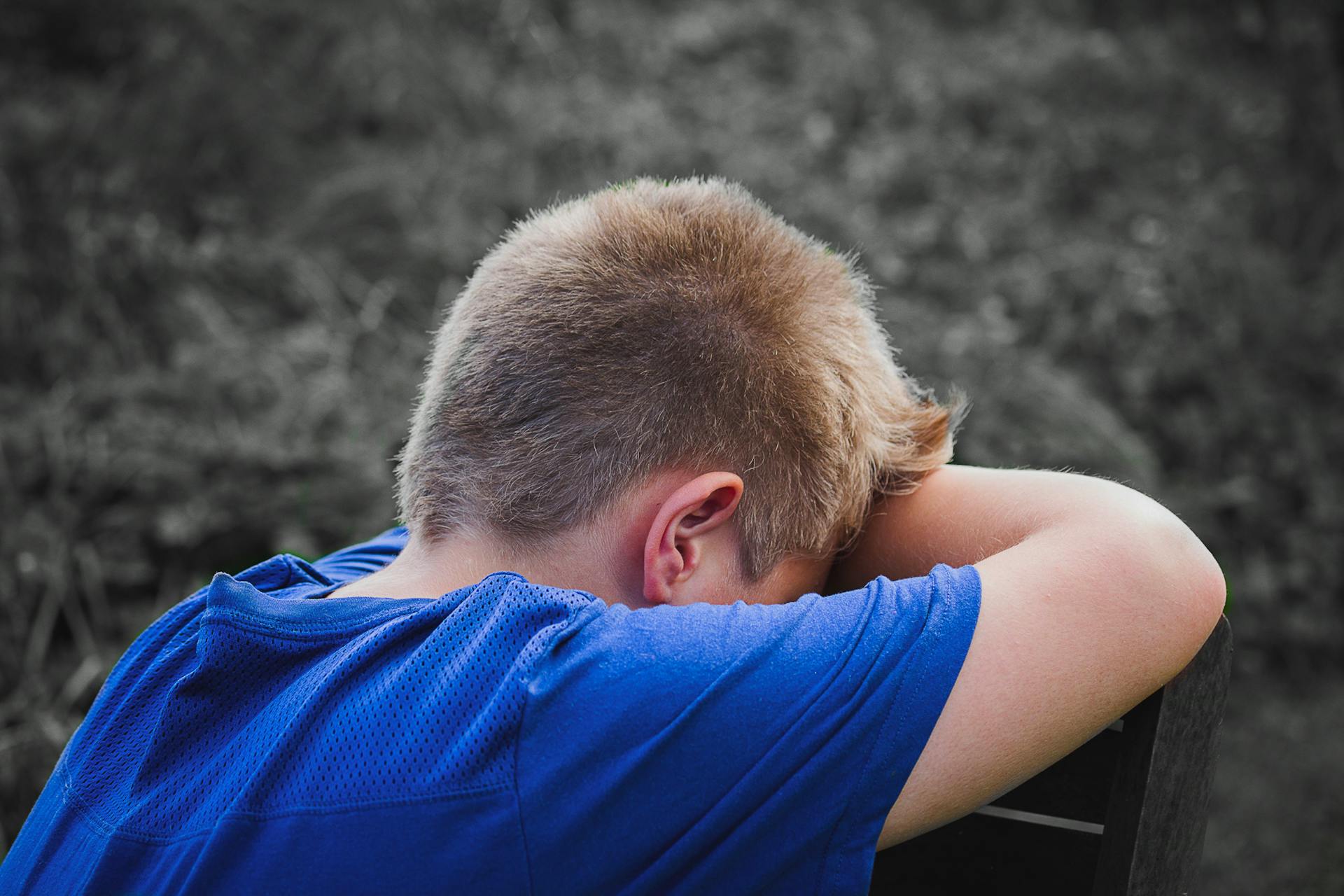Ein trauriger Junge lehnt an einem Holzstuhl | Quelle: Pexels