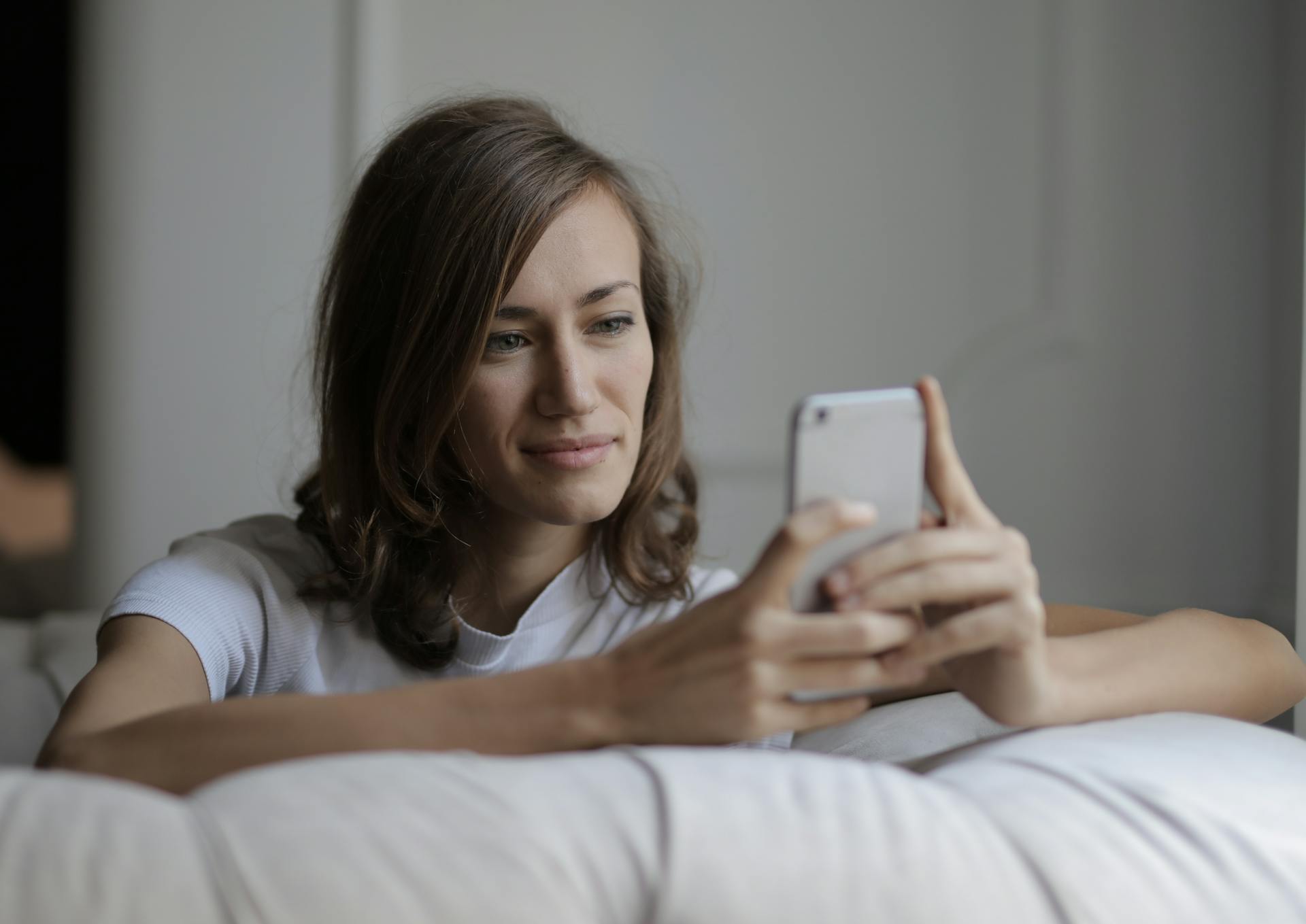 Eine Frau, die ihr Telefon anlächelt | Quelle: Pexels
