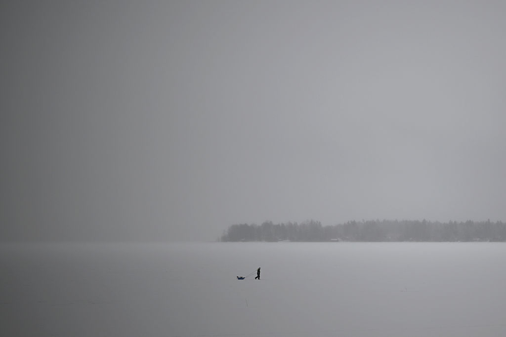 Ein Mann geht am 29. Januar 2022 während eines „weißen Tages“ im Kvarken-Archipel auf dem zugefrorenen Meer in der Nähe von Vaasa Eisfischen | Quelle: Getty Images