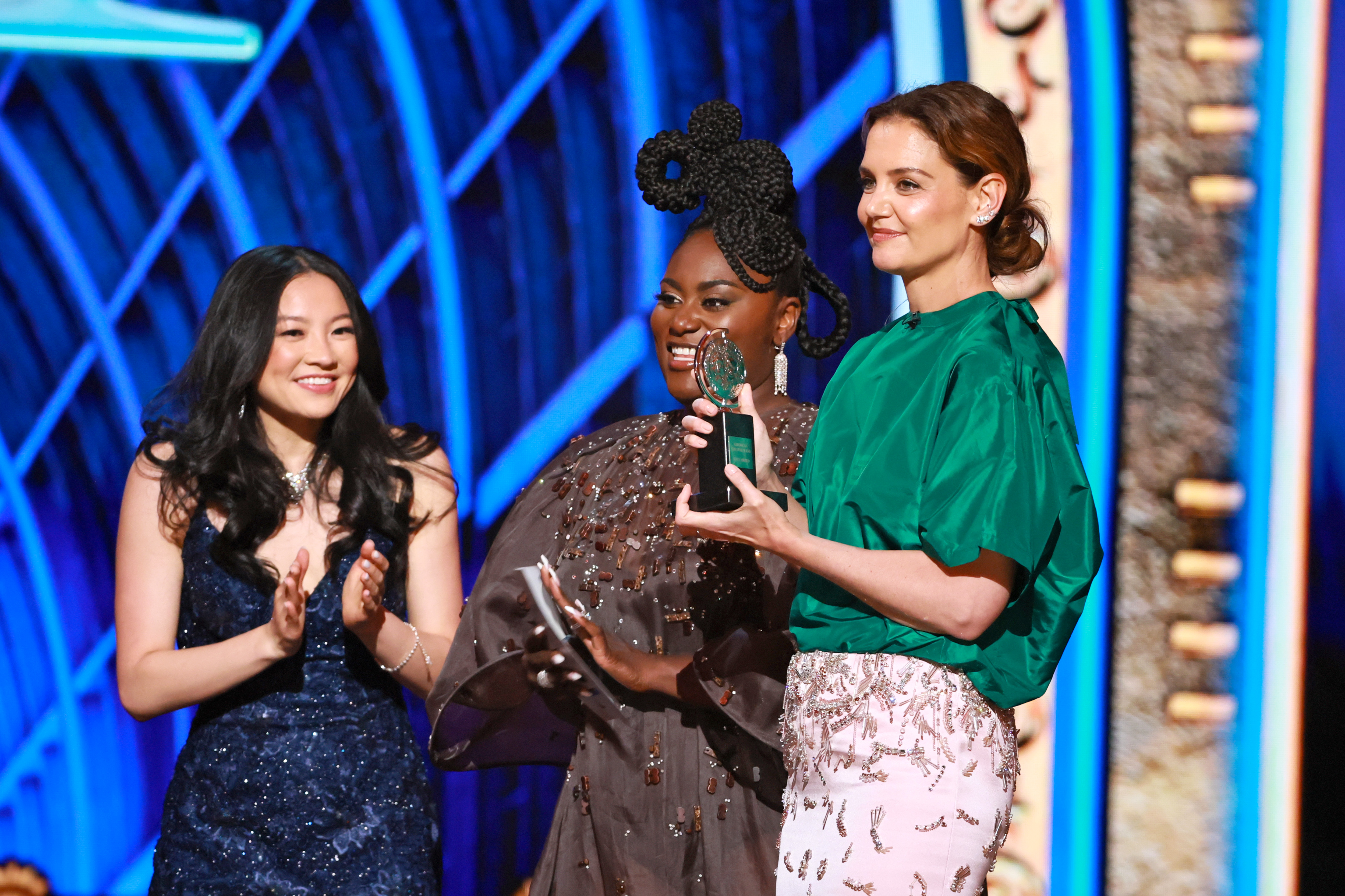 Katie Holmes feiert gemeinsam mit Danielle Brooks und einer lächelnden Preisträgerin auf der Bühne den Gewinn des Tony Awards. Der Moment spiegelt sowohl Stil als auch Freude wider: Holmes in ihrem herausragenden Ensemble applaudiert den Talenten des Abends.