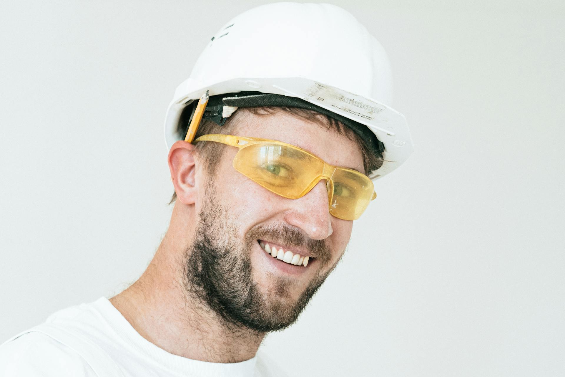 Ein lächelnder Bauarbeiter, der einen weißen Schutzhelm und eine gelbe Schutzbrille trägt | Quelle: Pexels
