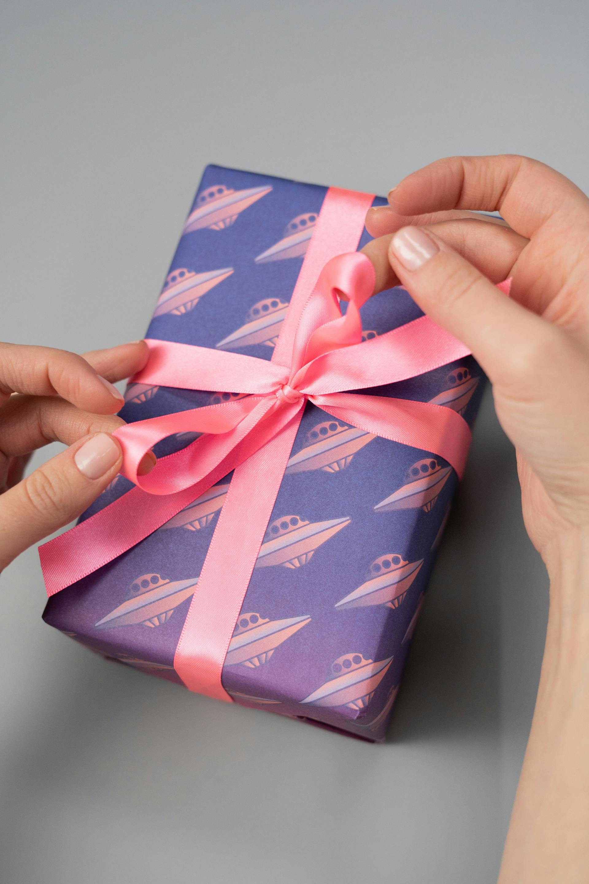 Eine Nahaufnahme einer Person, die einen Geschenkkarton mit einer rosa Schleife hält | Quelle: Pexels