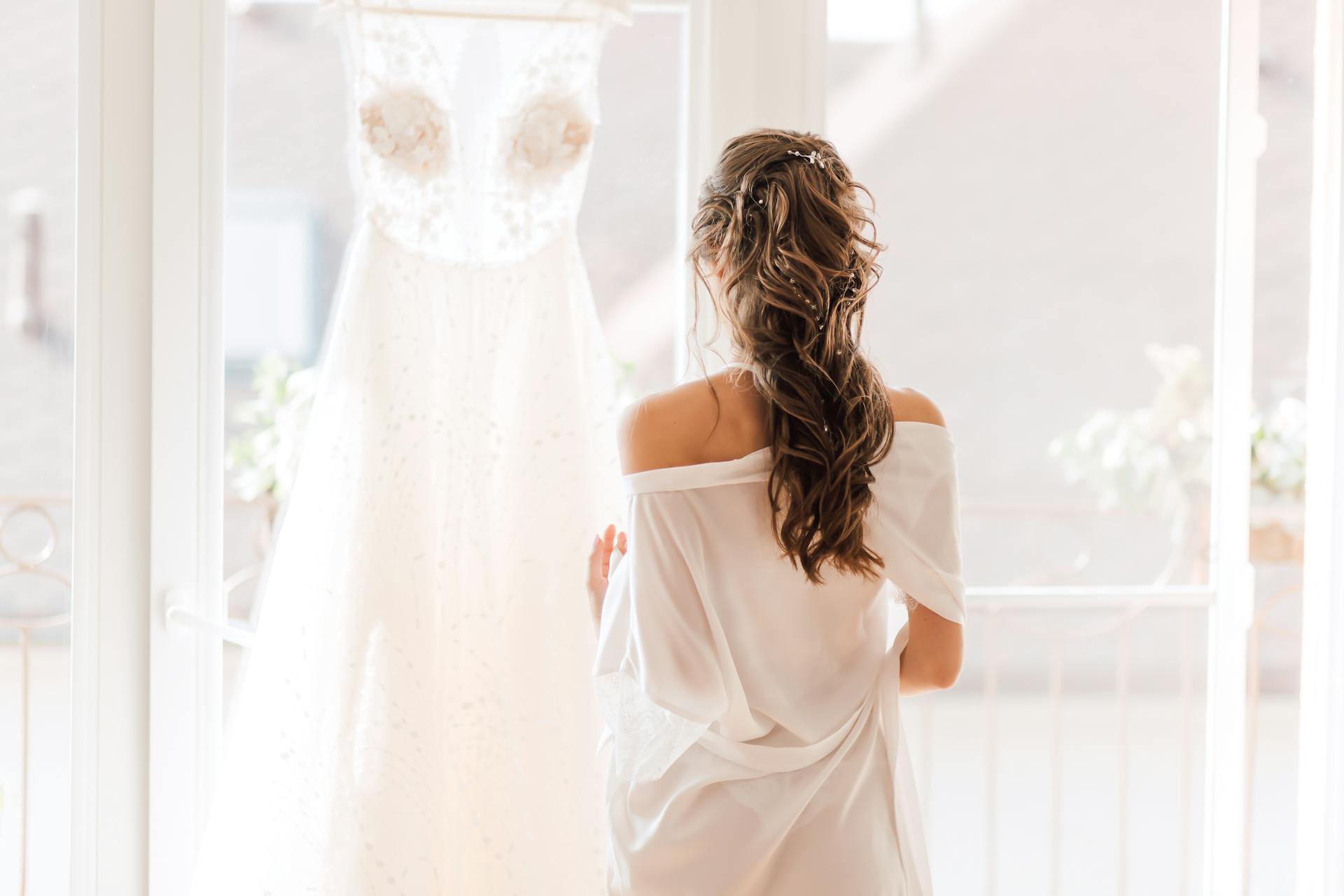 Eine Braut steht vor einem Hochzeitskleid | Quelle: Pexels