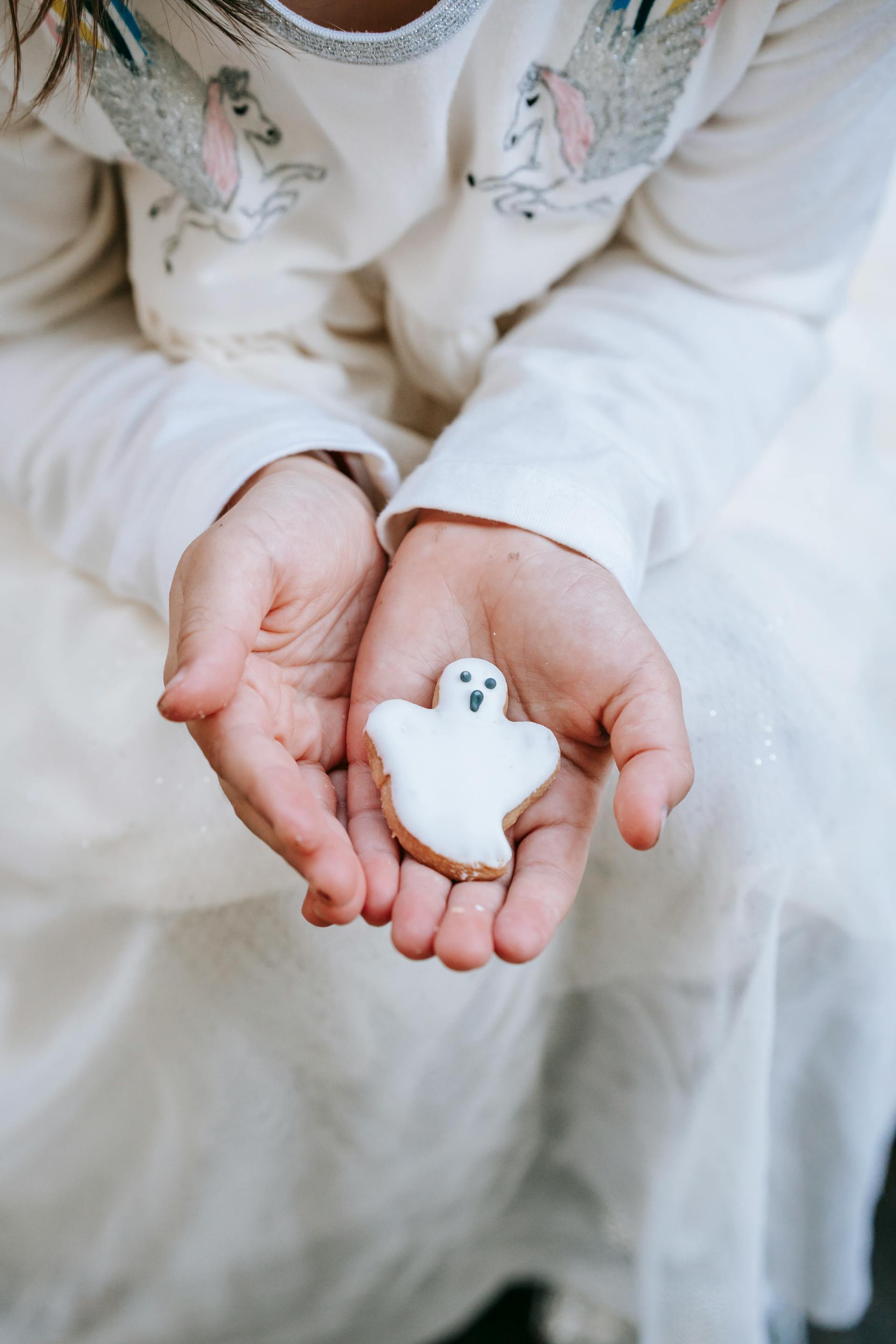 Ein kleines Mädchen hält einen Geisterkeks in den Händen | Quelle: Pexels