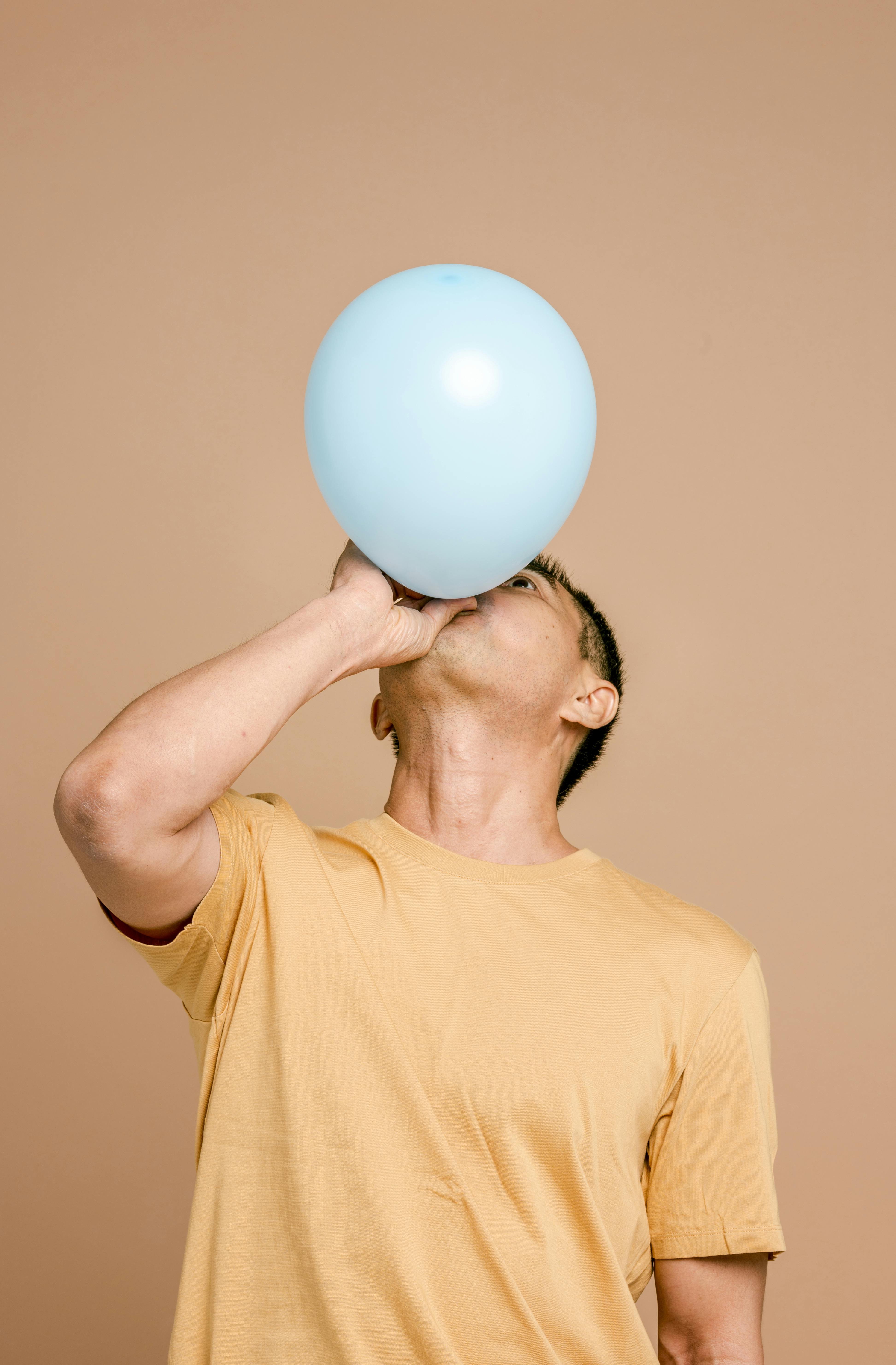Ein Mann bläst einen Luftballon auf | Quelle: Pexels