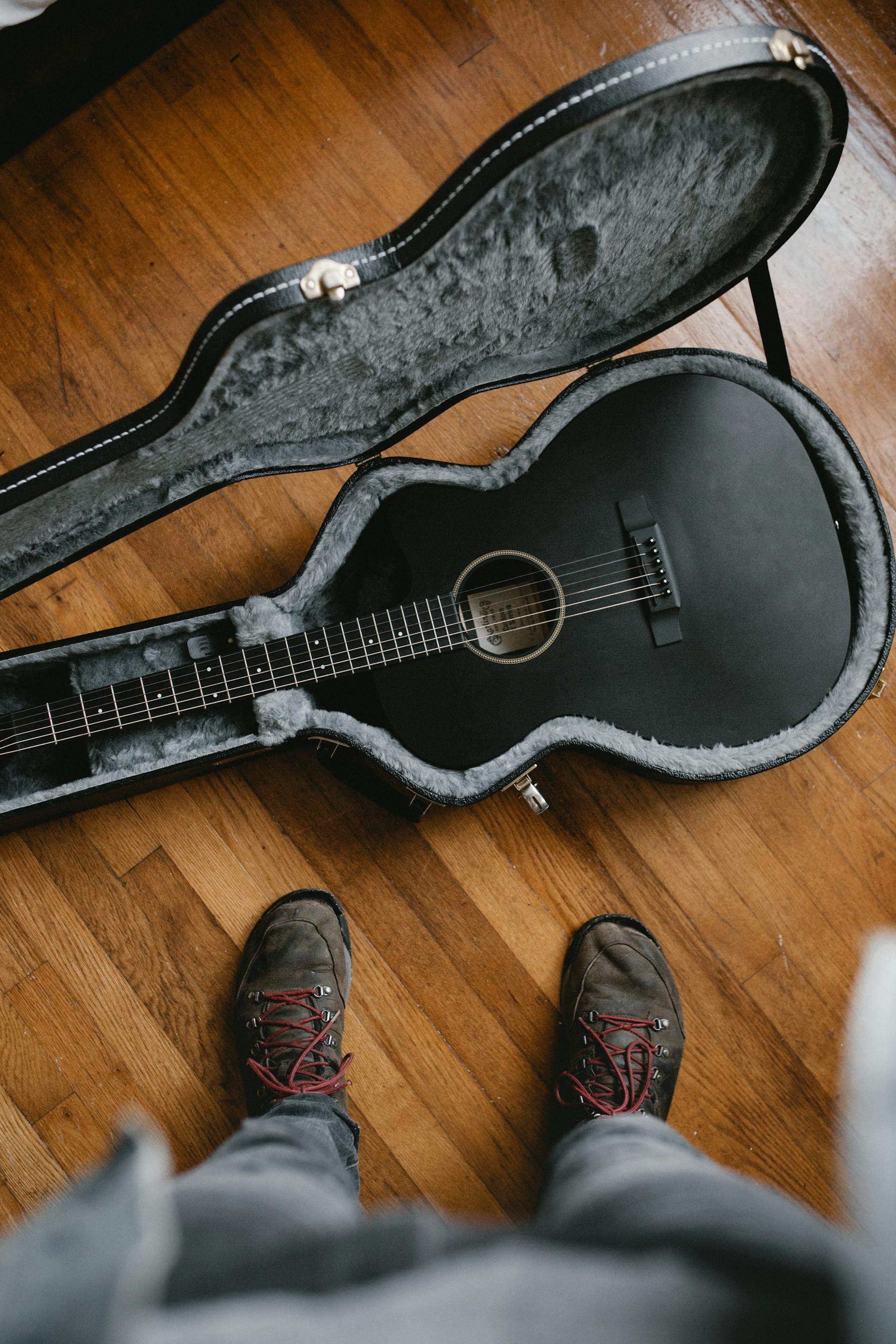 Ein Mann steht neben einer Gitarre | Quelle: Pexels