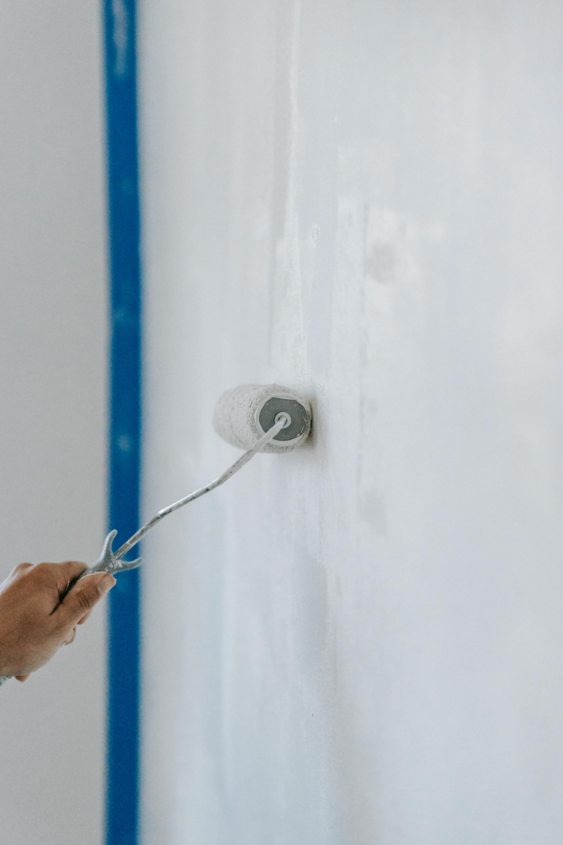 Eine Person, die die Wand mit einer Walze streicht | Quelle: Pexels