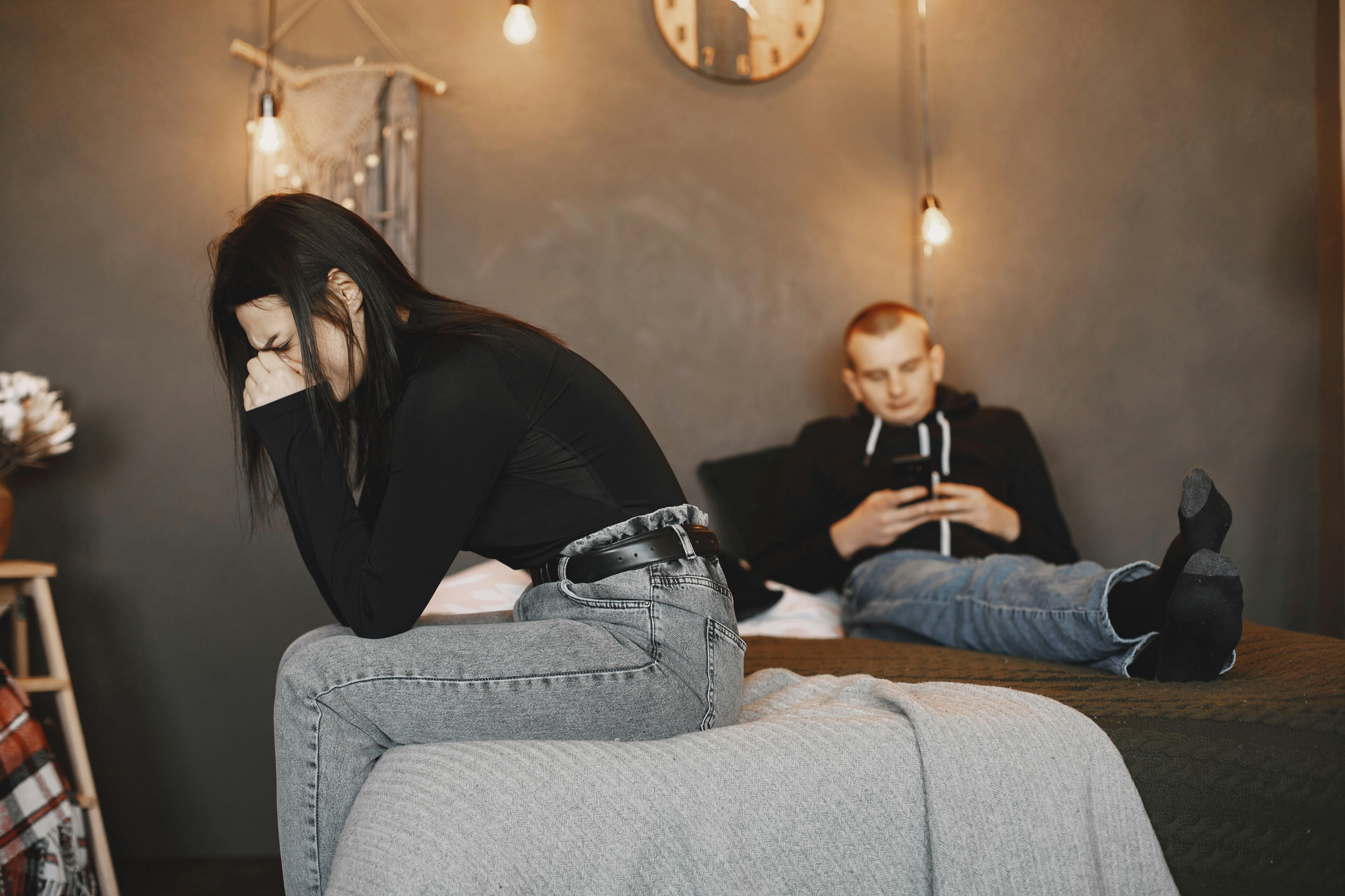 Eine weinende Frau, während ihr Mann an seinem Handy sitzt | Quelle: Pexels