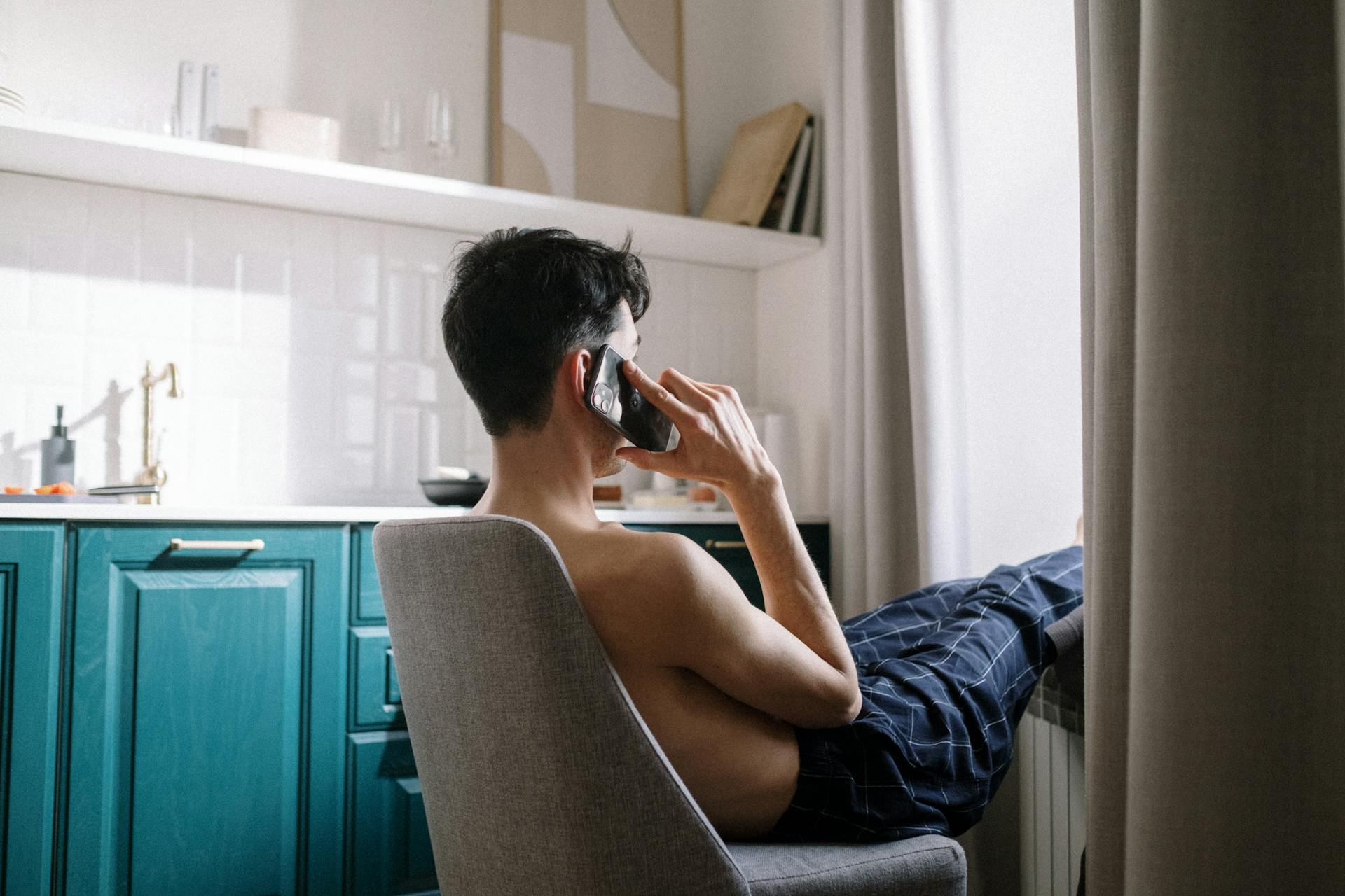 Eine Seitenansicht eines Mannes, der auf einem Stuhl sitzt und telefoniert | Quelle: Pexels