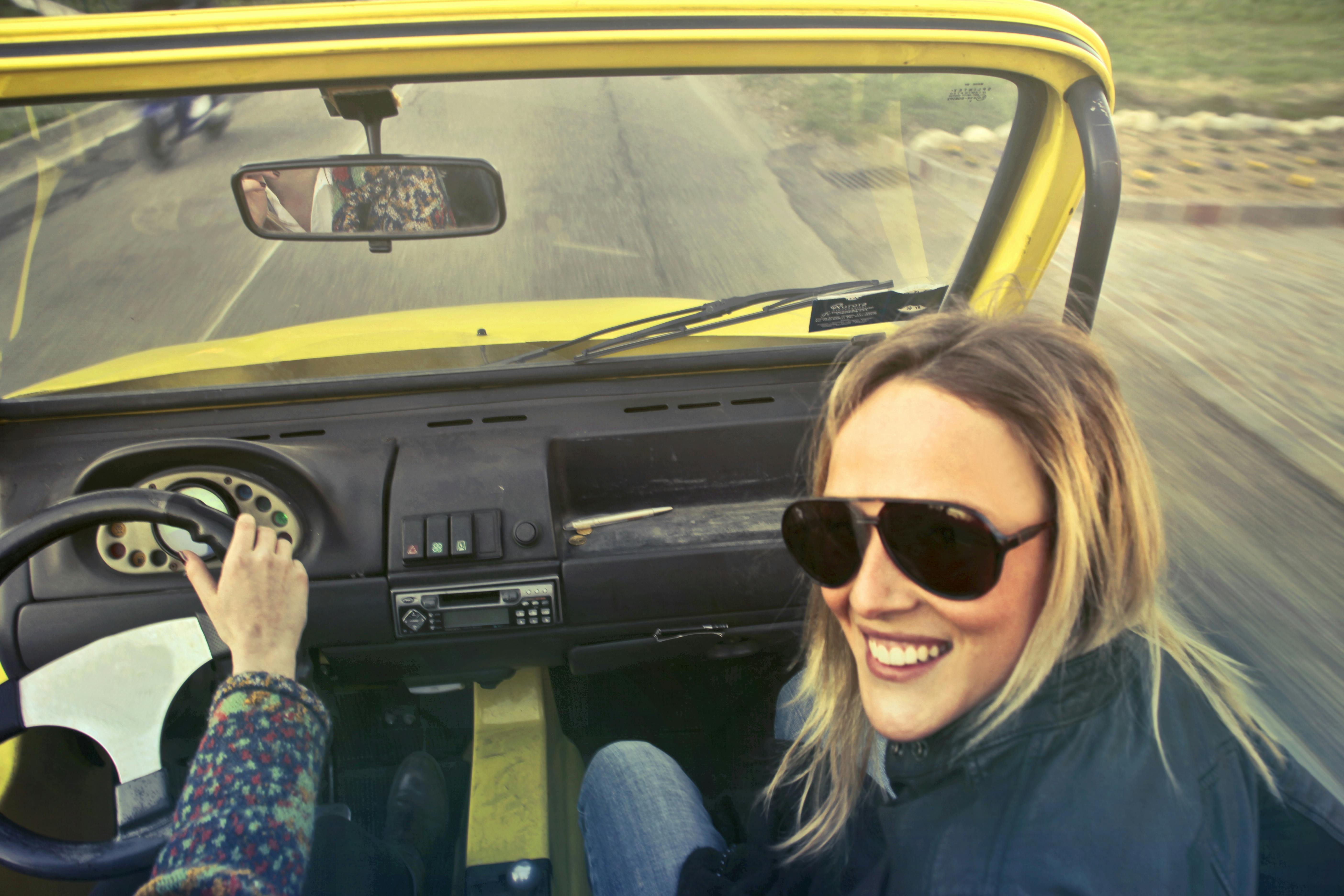 Eine Frau lacht, während sie in einem Auto sitzt | Quelle: Pexels