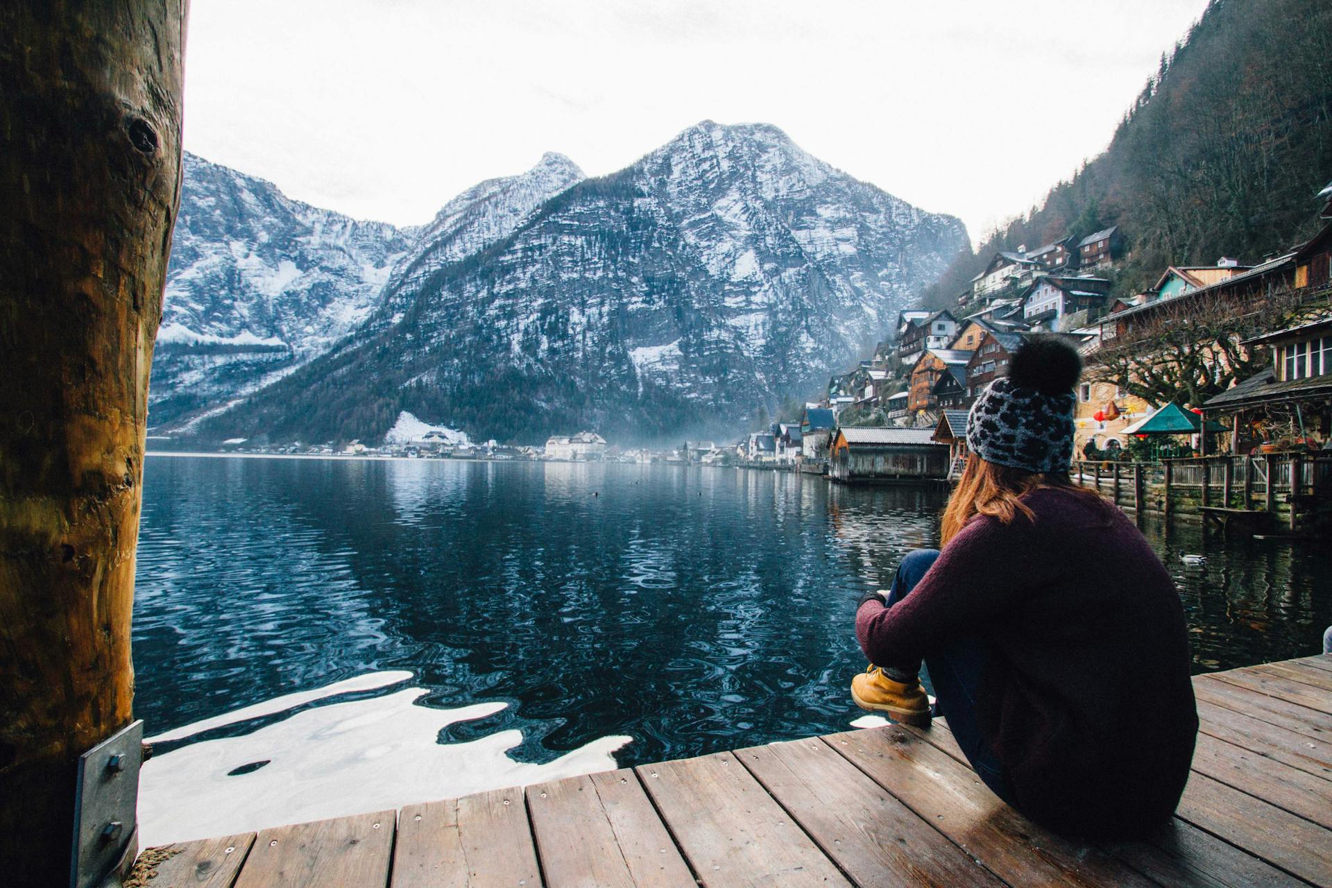 Eine Frau sitzt auf einem Holzdeck und blickt auf den See und die Berge | Quelle: Pexels