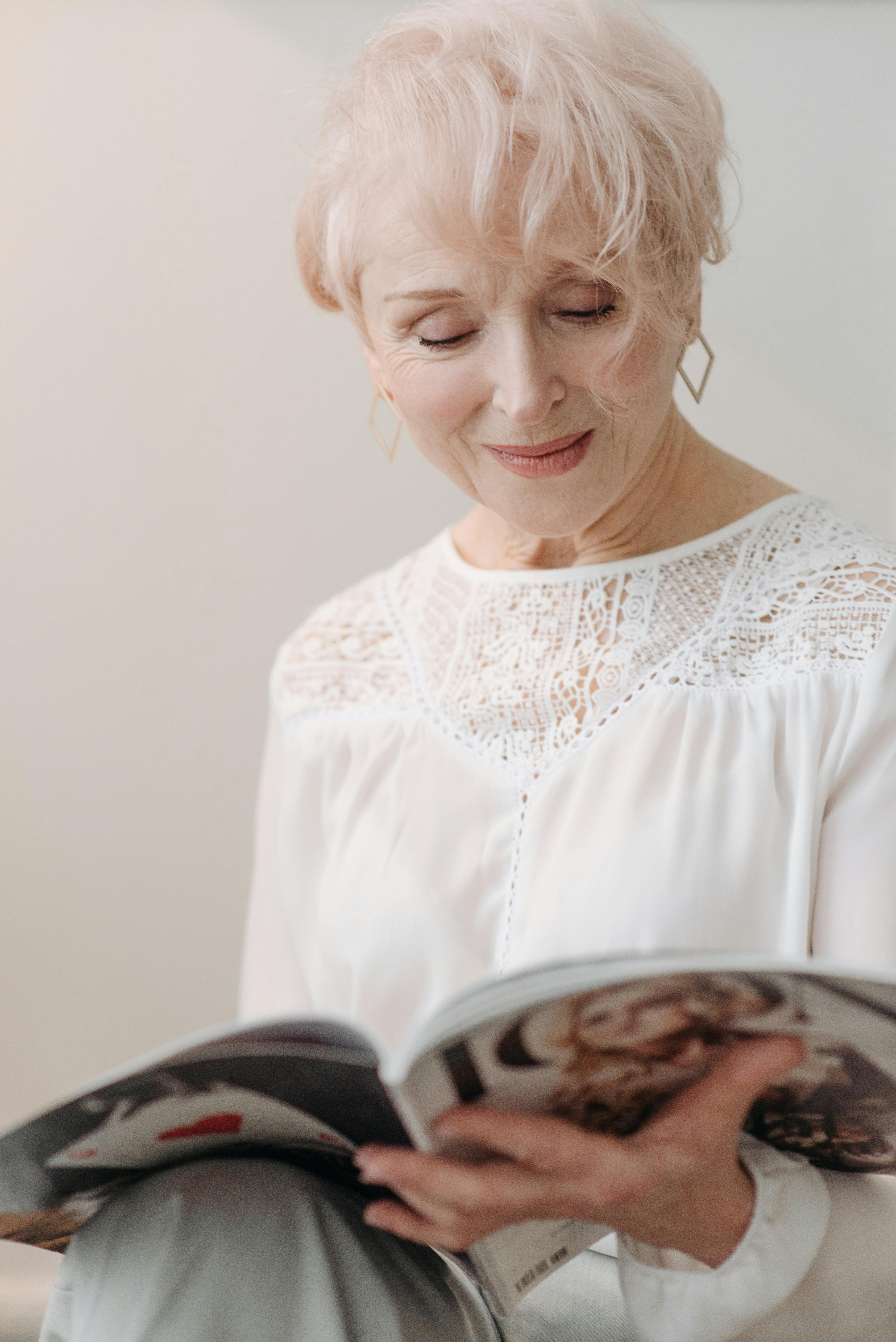 Eine lächelnde ältere Frau, die eine Zeitschrift liest | Quelle: Pexels