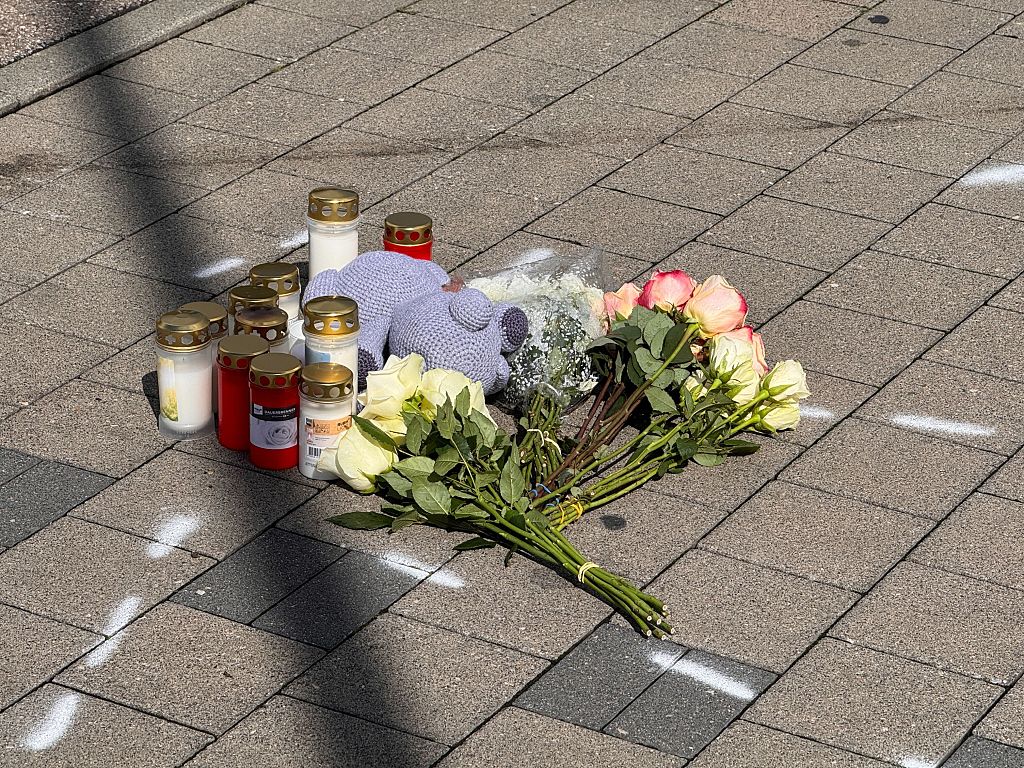 Menschen hinterlegen Blumen und Kerzen am Ort des Geschehens | Quelle: Getty Images