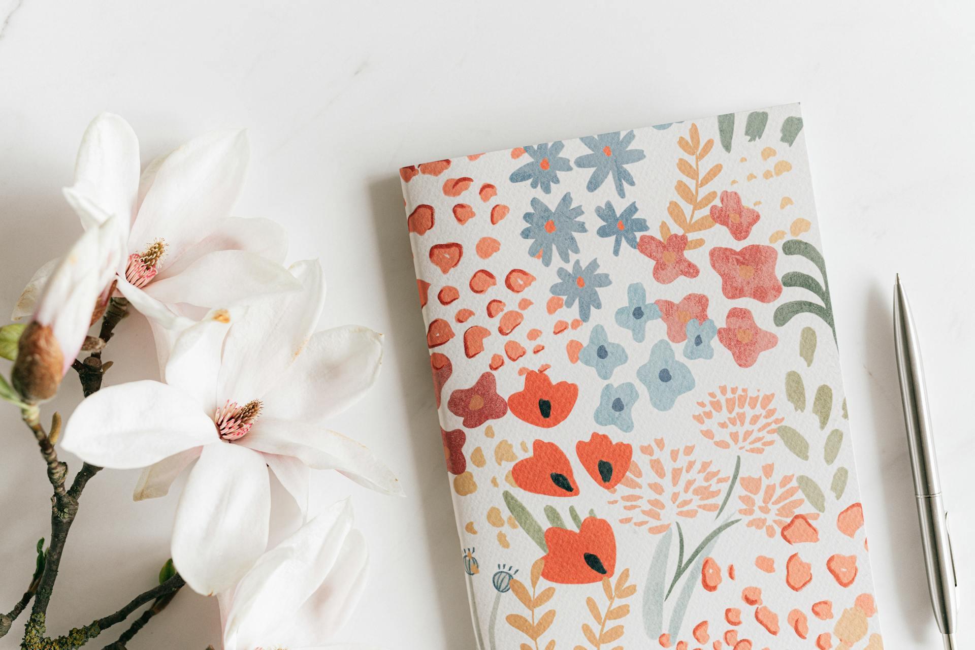Ein Tagebuch und ein Stift liegen neben weißen Blumen | Quelle: Pexels