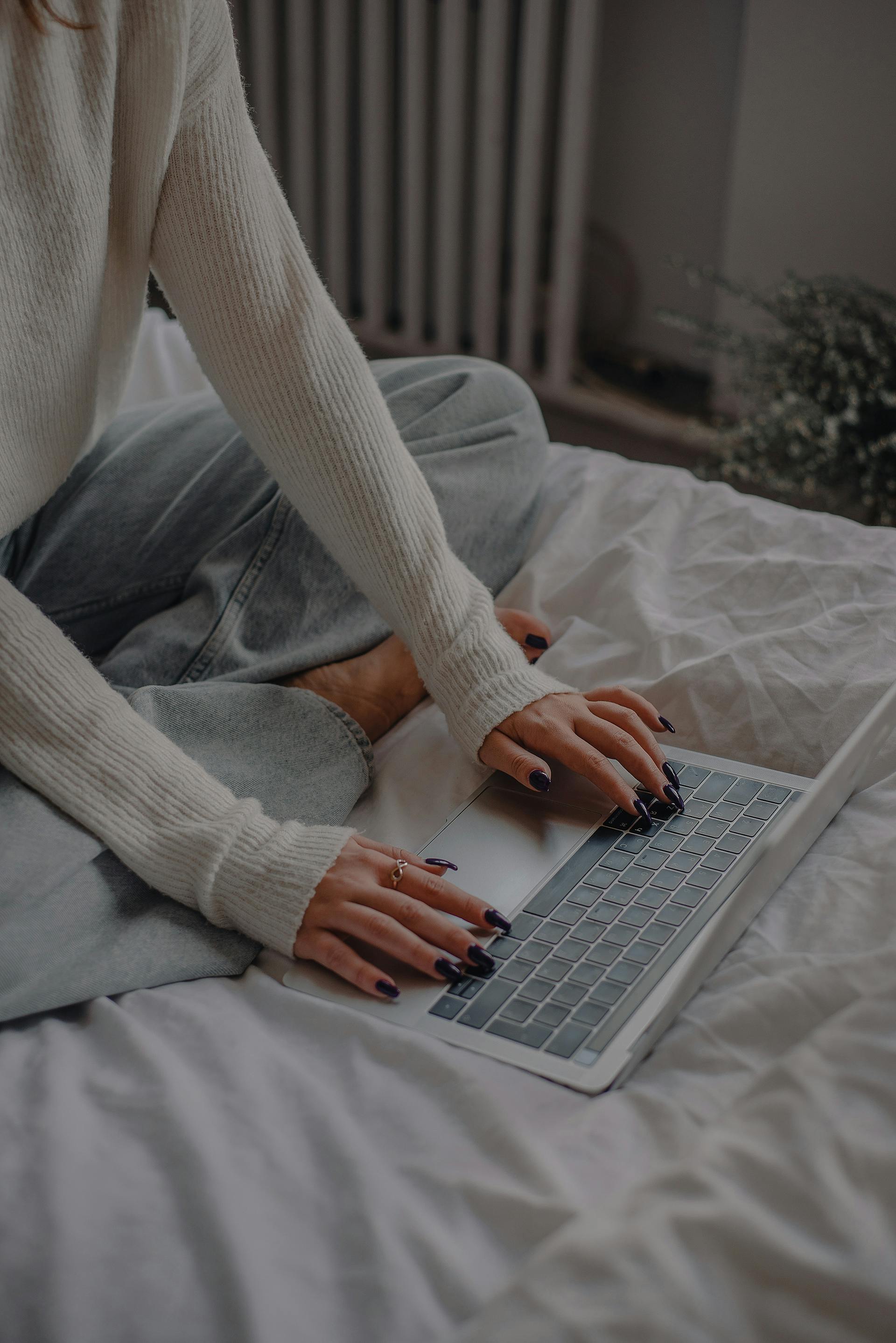 Eine Nahaufnahme einer Frau, die ihren Laptop im Bett benutzt | Quelle: Pexels