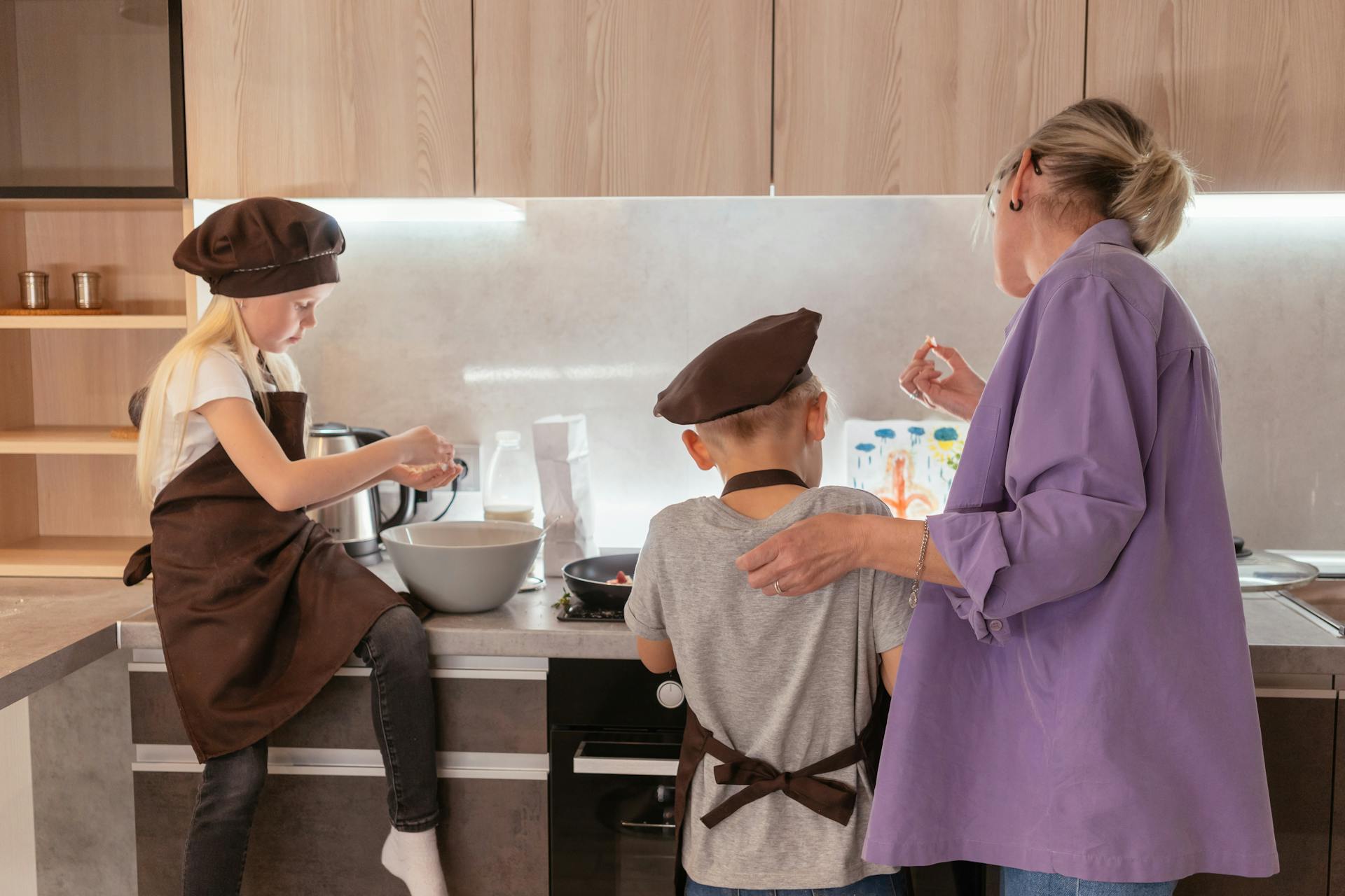 Eine Oma steht neben ihren Enkelkindern in der Küche | Quelle: Pexels