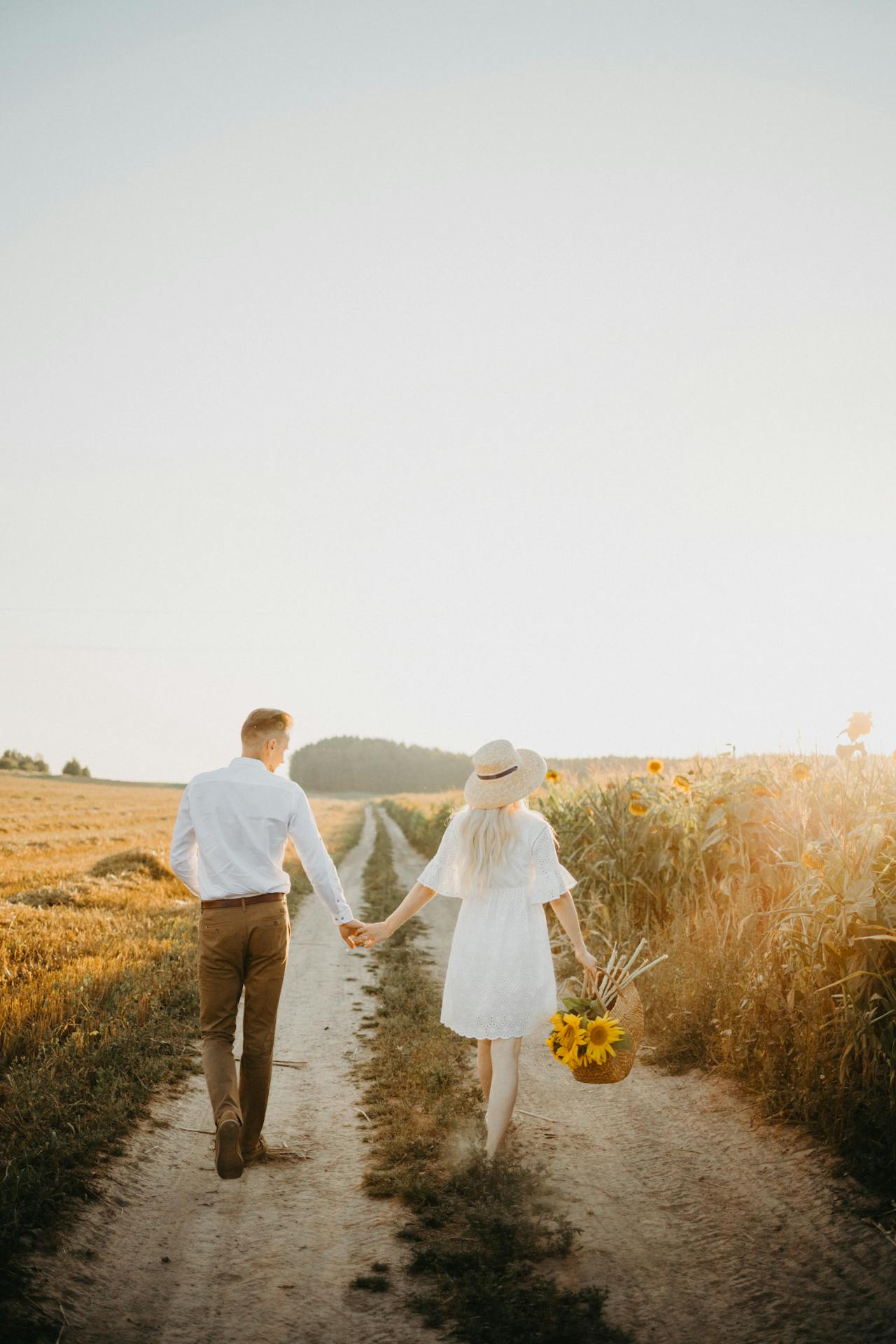 Eine Frau hält einen Korb mit Sonnenblumen und geht mit einem Mann spazieren | Quelle: Pexels
