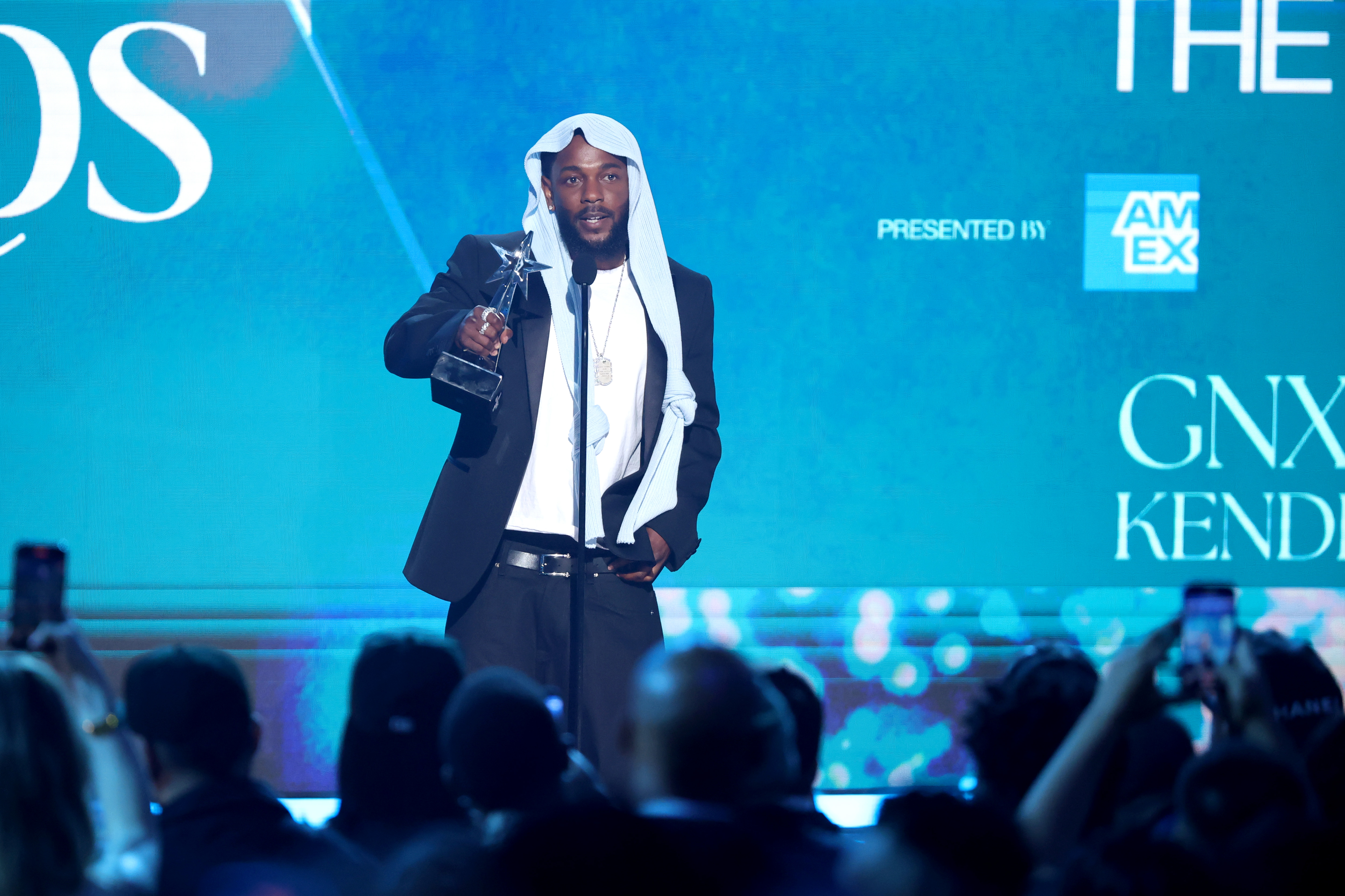Kendrick Lamar wendet sich an das Publikum, nachdem er bei den BET Awards 2025 in Los Angeles einen Preis erhalten hat. Der Rapper trug einen eleganten schwarzen Anzug und seine virale Kopfbedeckung und sah im Rampenlicht sowohl stilvoll als auch nachdenklich aus.